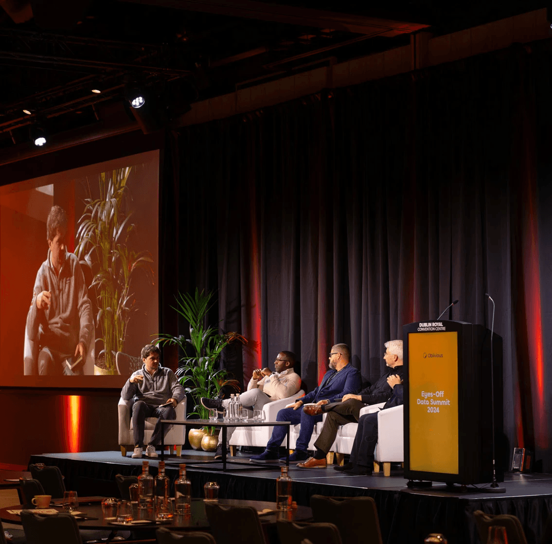 Speakers of Eyes-Off Data Summit sitting on the couch on the stage of the summit.