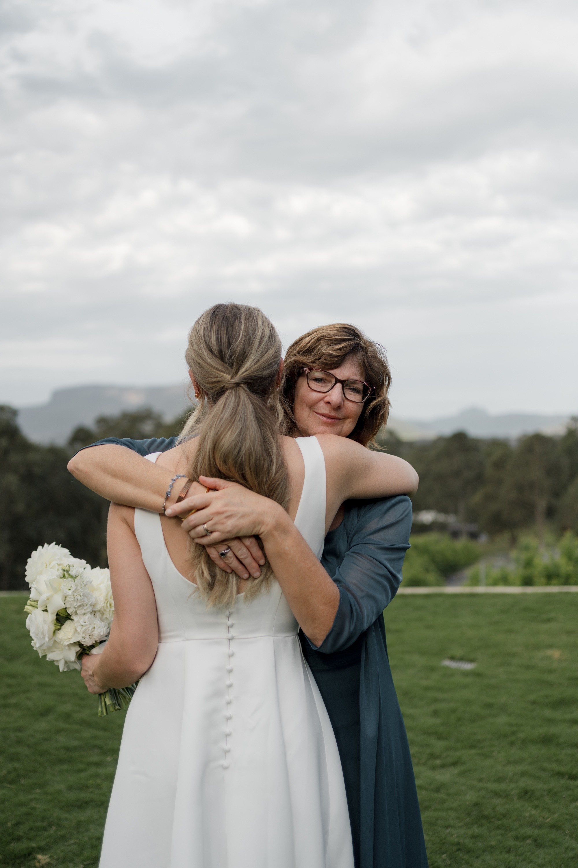 Bride embracing a guest after an outdoor wedding ceremony