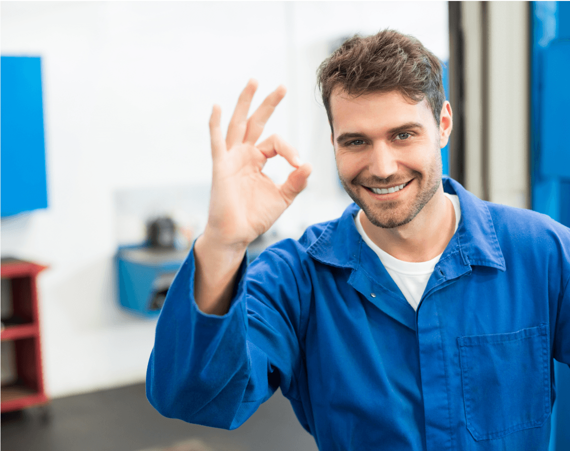 A smiling technician in a blue uniform giving an 'okay' hand gesture, representing customer satisfaction.