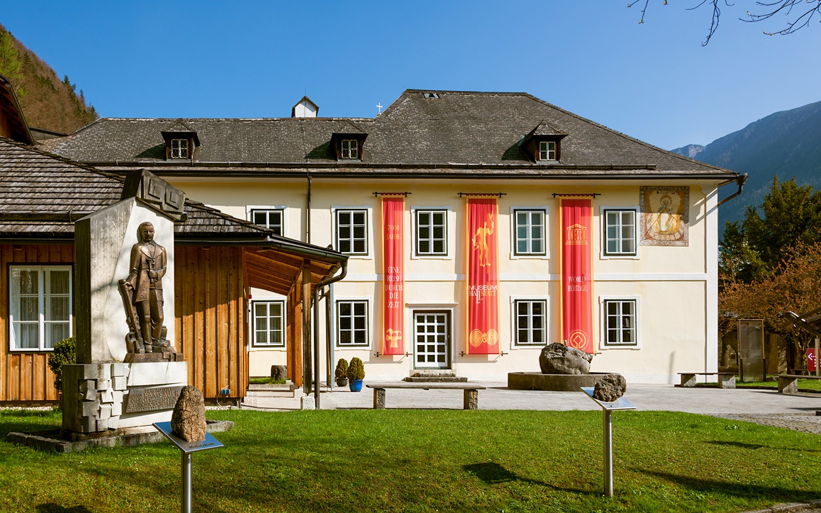 Hallstatt Museum exterior with red banners and historical statue in Austria.
