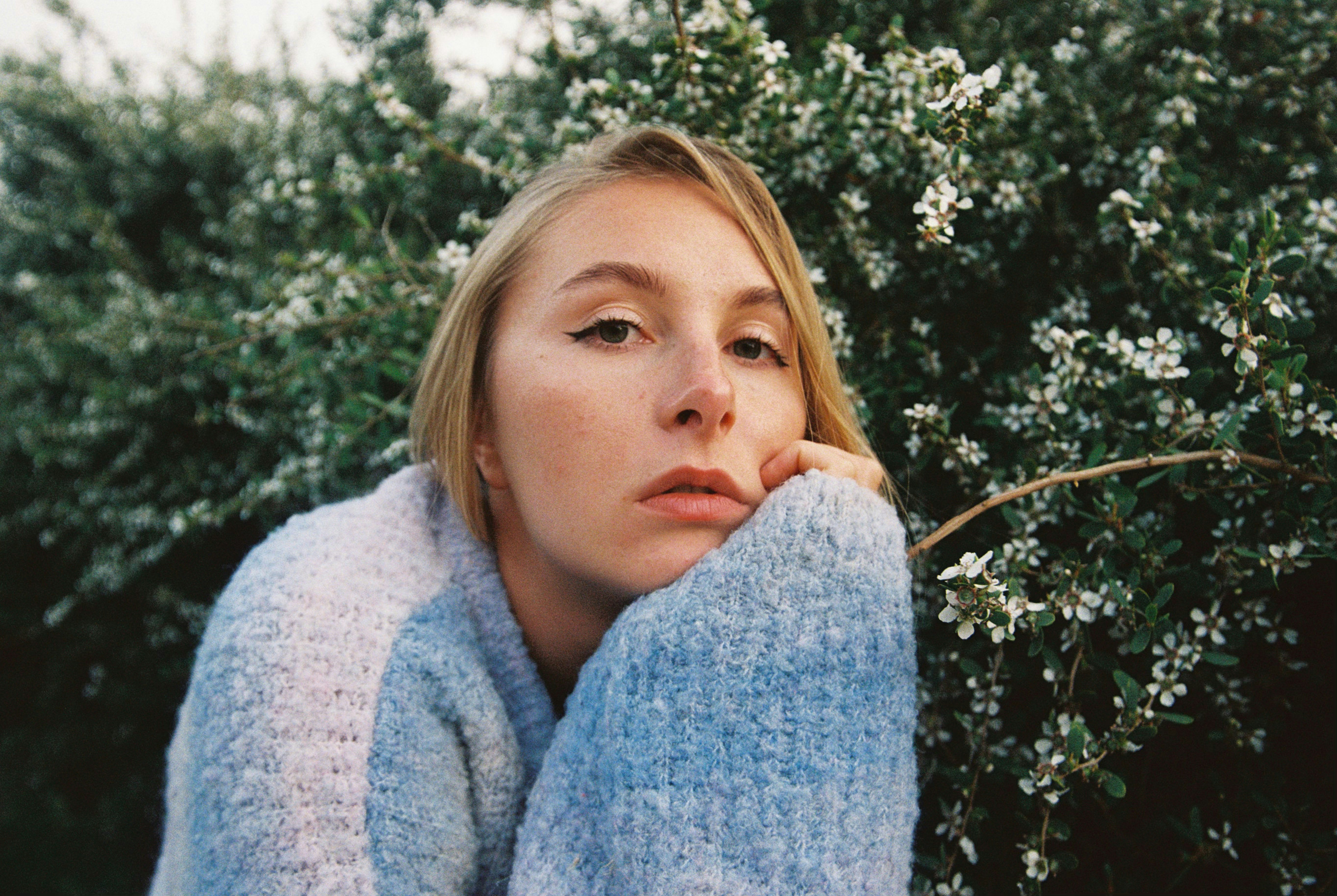 A young woman with blonde hair wearing a sweater.