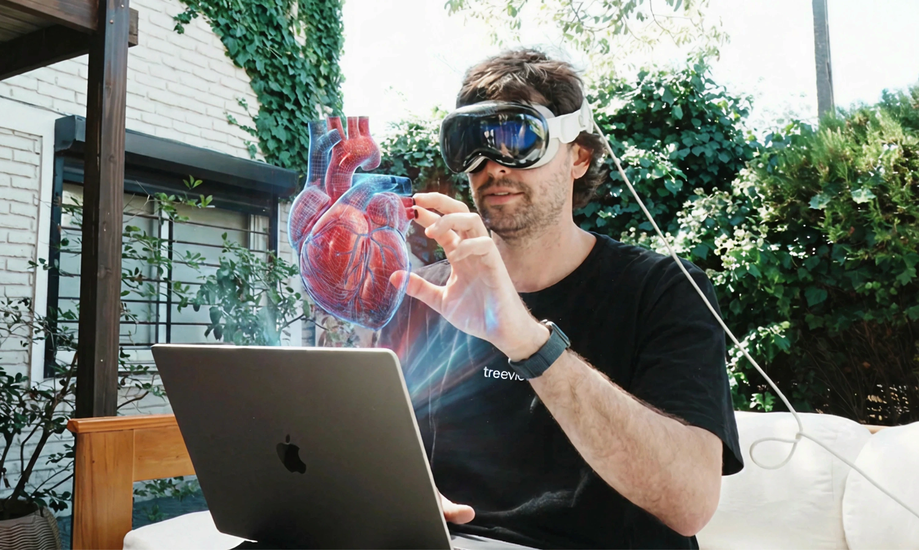 Treeview developer wearing Apple Vision Pro headset while interacting with a 3D holographic heart model, demonstrating spatial computing for cardiovascular digital twin applications in healthcare