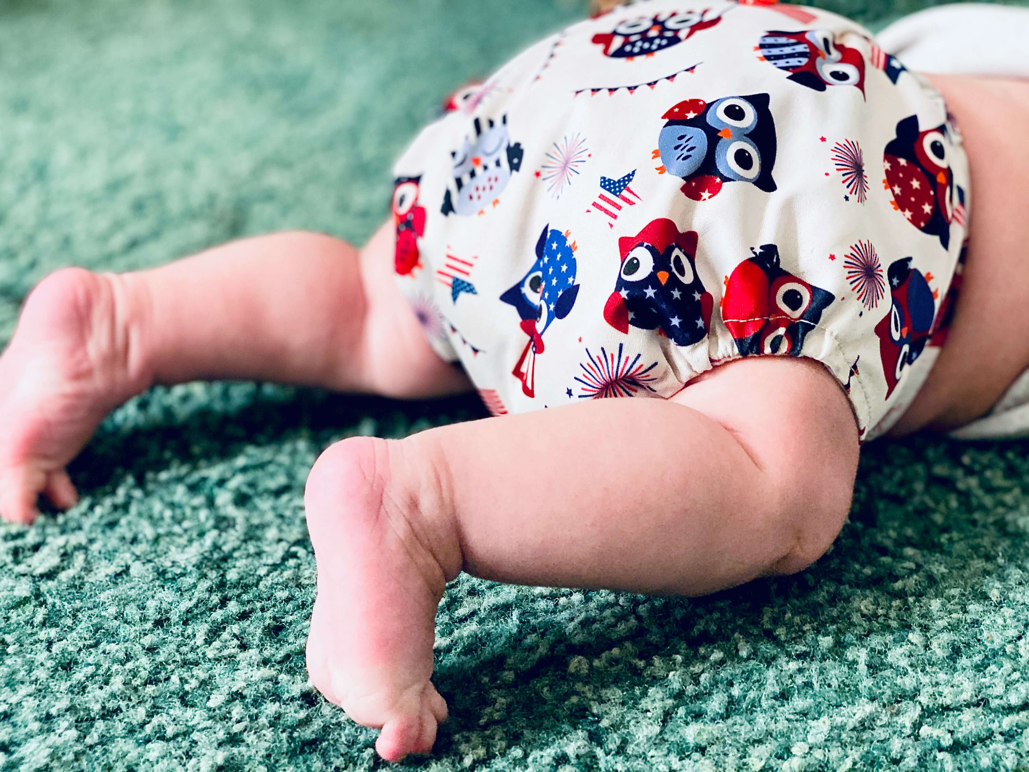 A baby wearing a decorated diaper on a carpet.