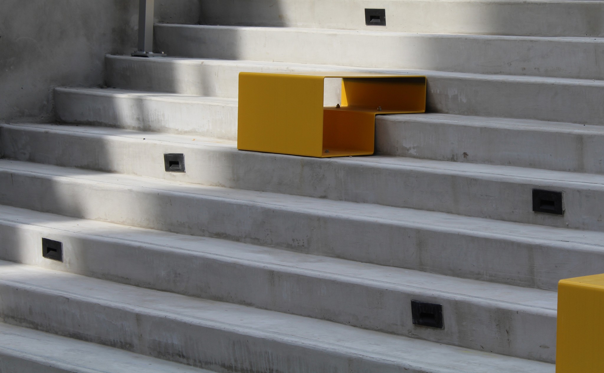 Photo of a yellow square metal sculpture resting on some steps