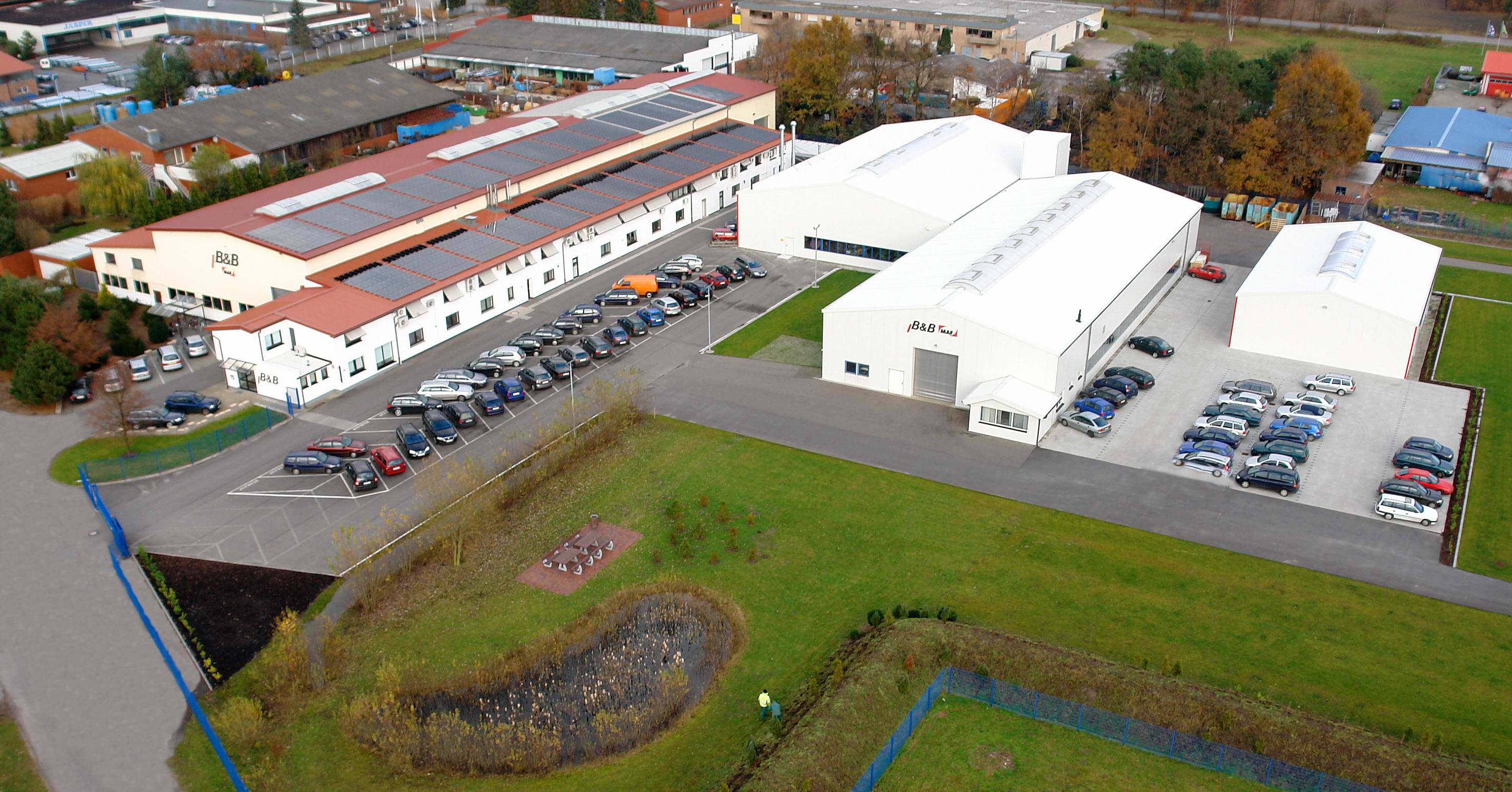 Luftaufnahme des Firmengebäudes mit Parkplatz. Gebäude mit Solarpanelen und Autos. 