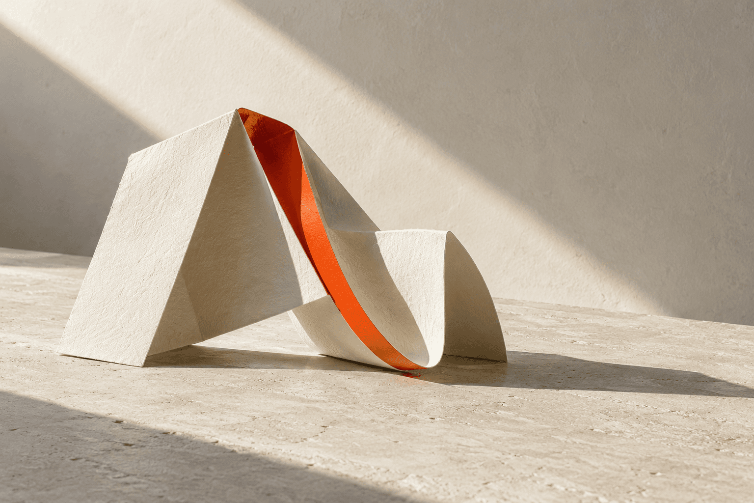 Original cream folded-paper still life with one orange-red fold in hard daylight.