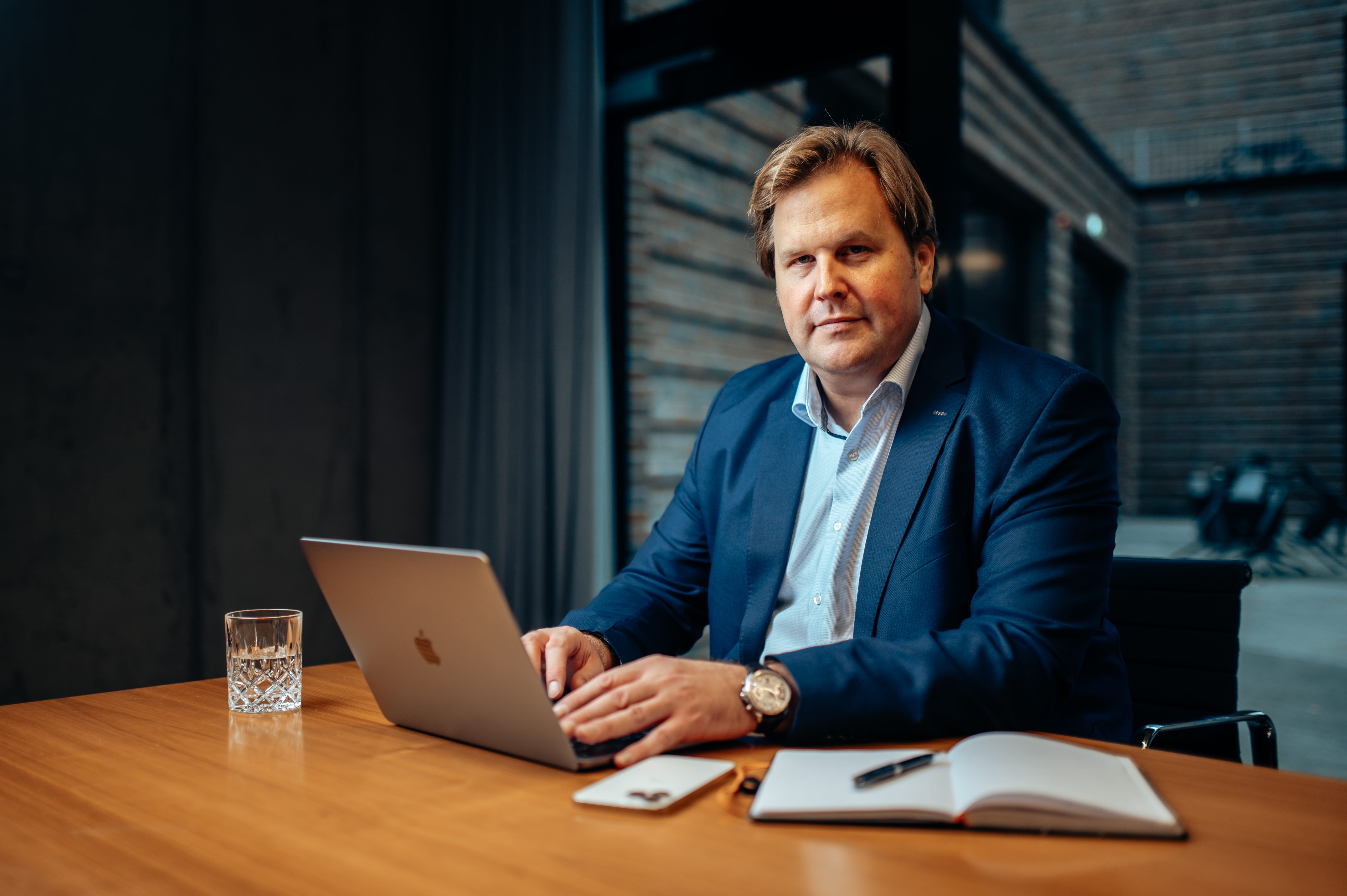 Holger Lentz, Geschäftsführender Gesellschafter von Commerce Partner sitzt am Tisch und schaut in die Kamera.