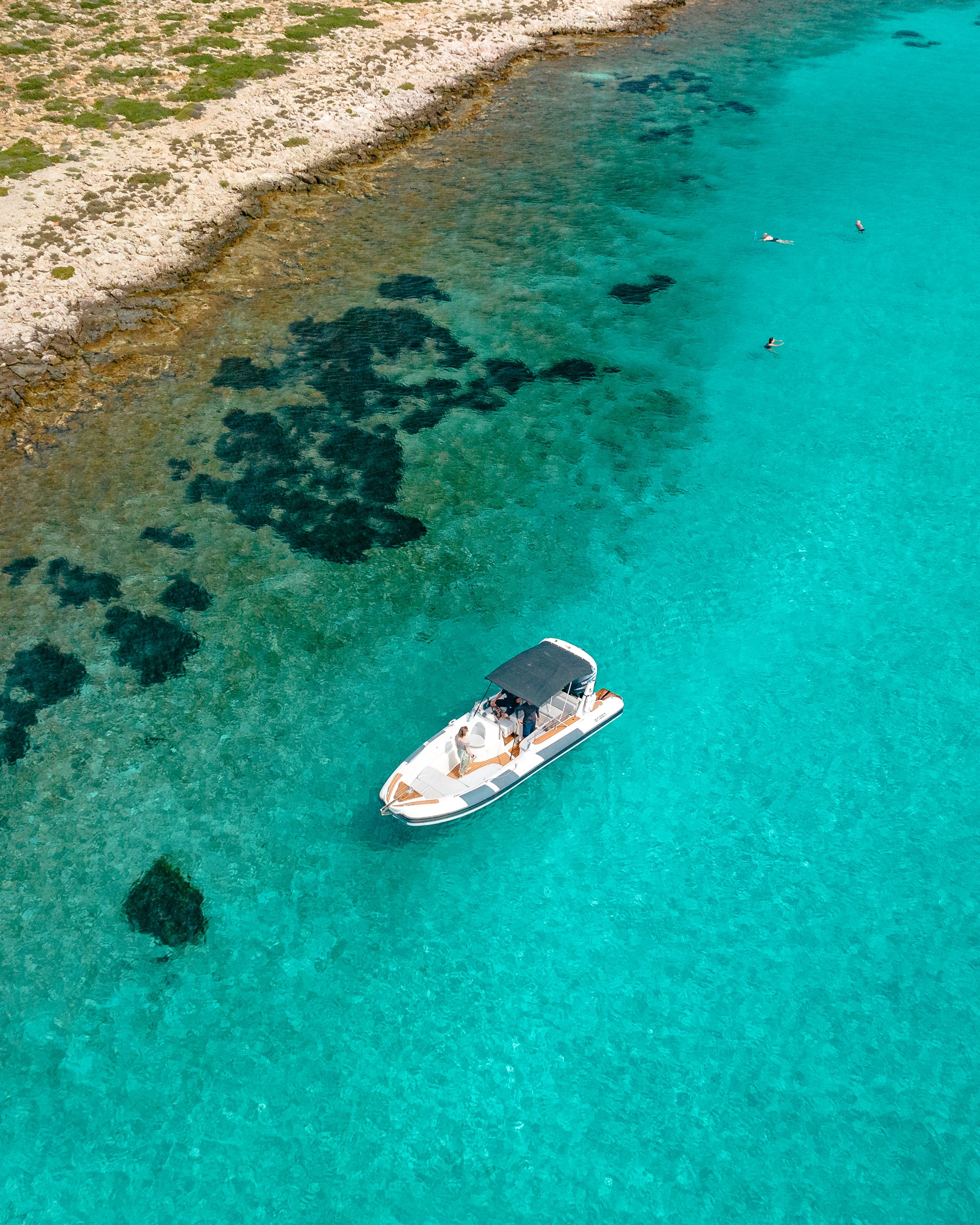 White Rock 36 speedboat with captain at helm cruising calm blue waters near Paros coastline with hills in background.