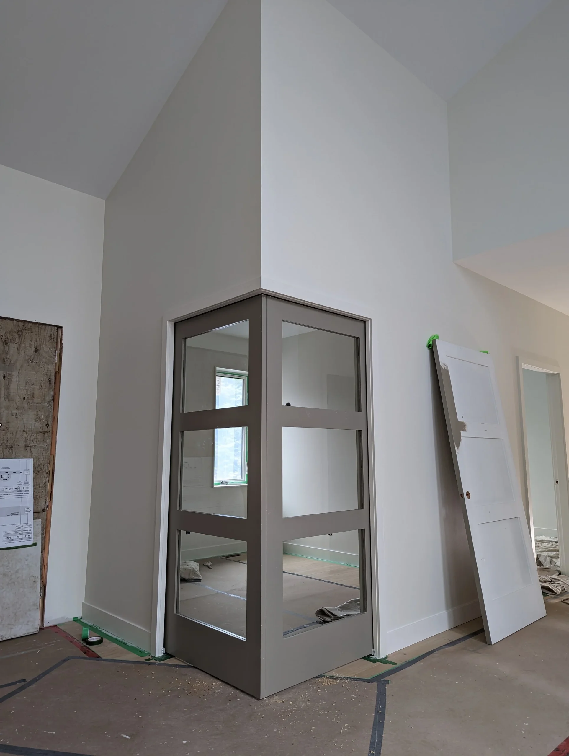 Modern two-story home with large glass windows, warmly lit interiors, and a balcony. Surrounded by trees and a manicured lawn at dusk. Cozy ambiance.