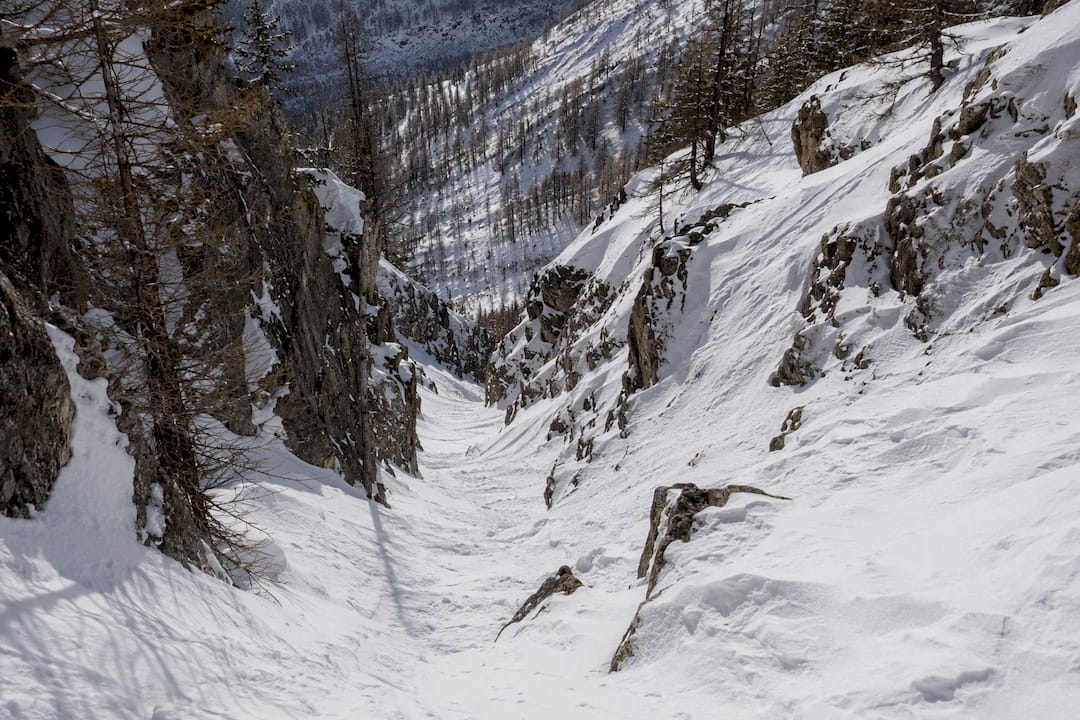 Narrow snow-filled couloir in mountain terrain