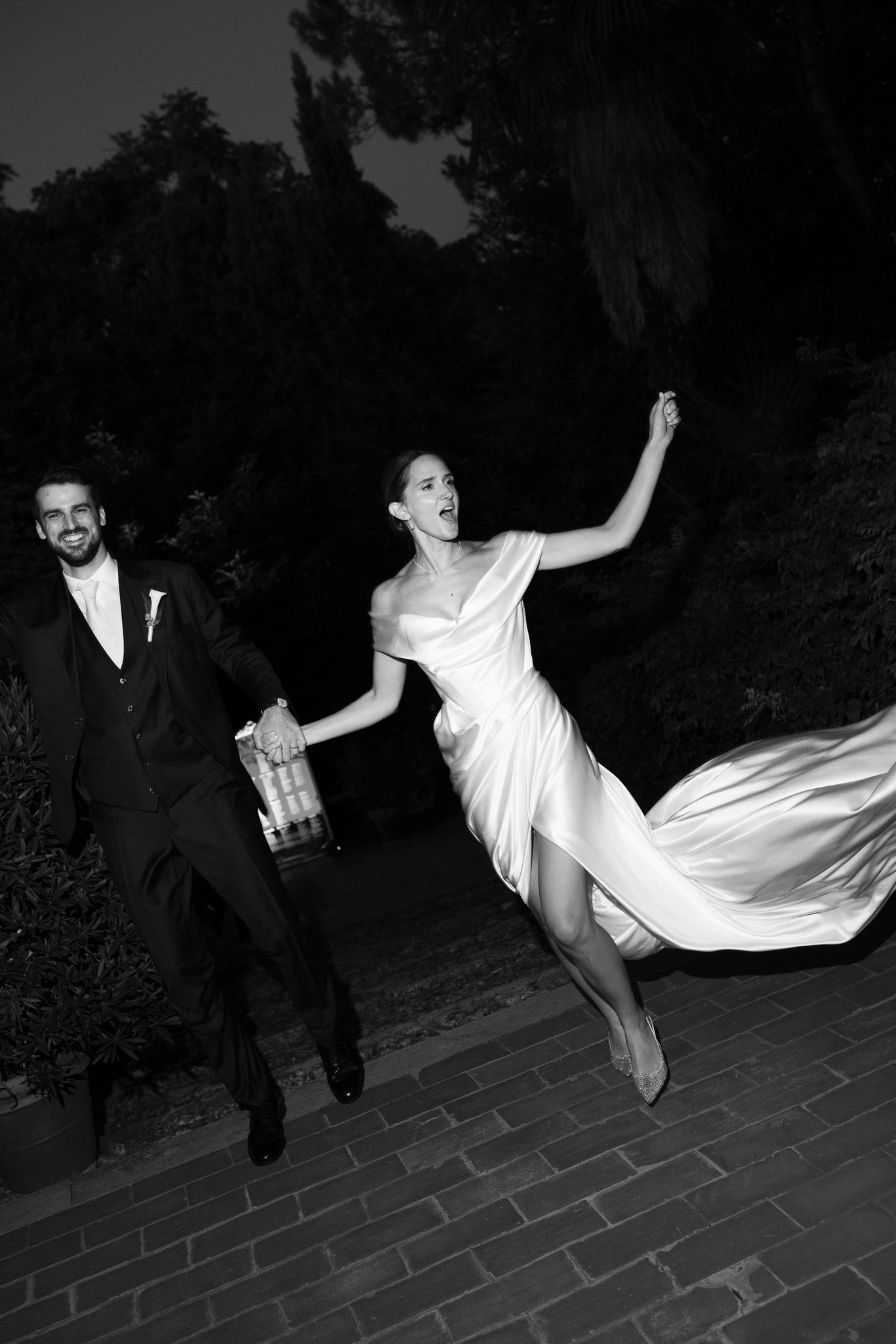 Sposi corrono di notte al Castello di Scipione, abito bianco svolazzante, reportage matrimoniale in bianco e nero