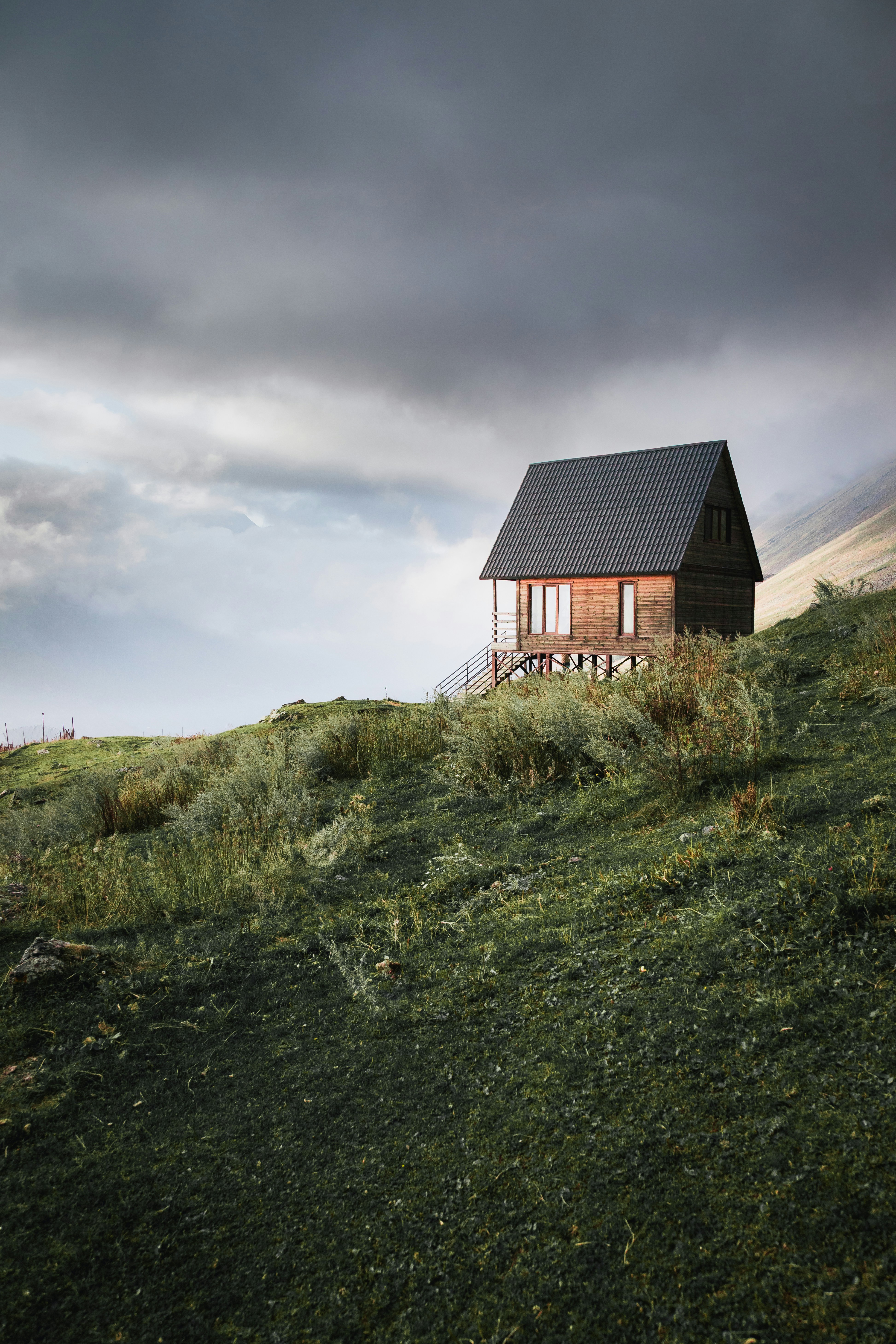 A small wooden cabin sits on a grassy hill.