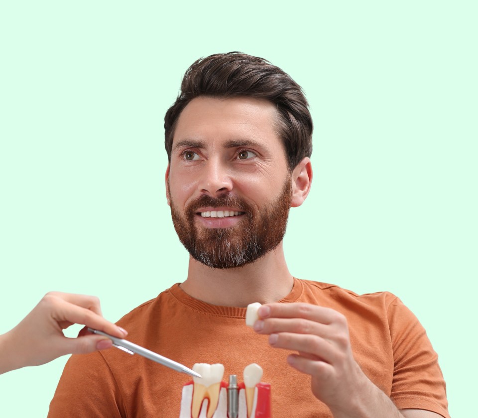 Mann bruker tannmodell for å vise riktig tannpuss og god munnhygiene.