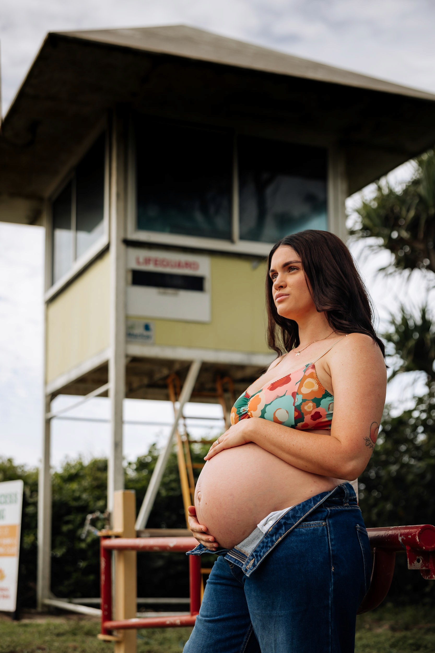 Pregnant woman posing at Mackay Surf Life Saving Club during creative maternity photos in Queensland