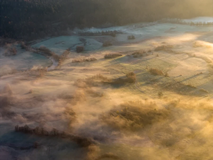 Aerial view over misty fields lit by the rising sun in Slovenia