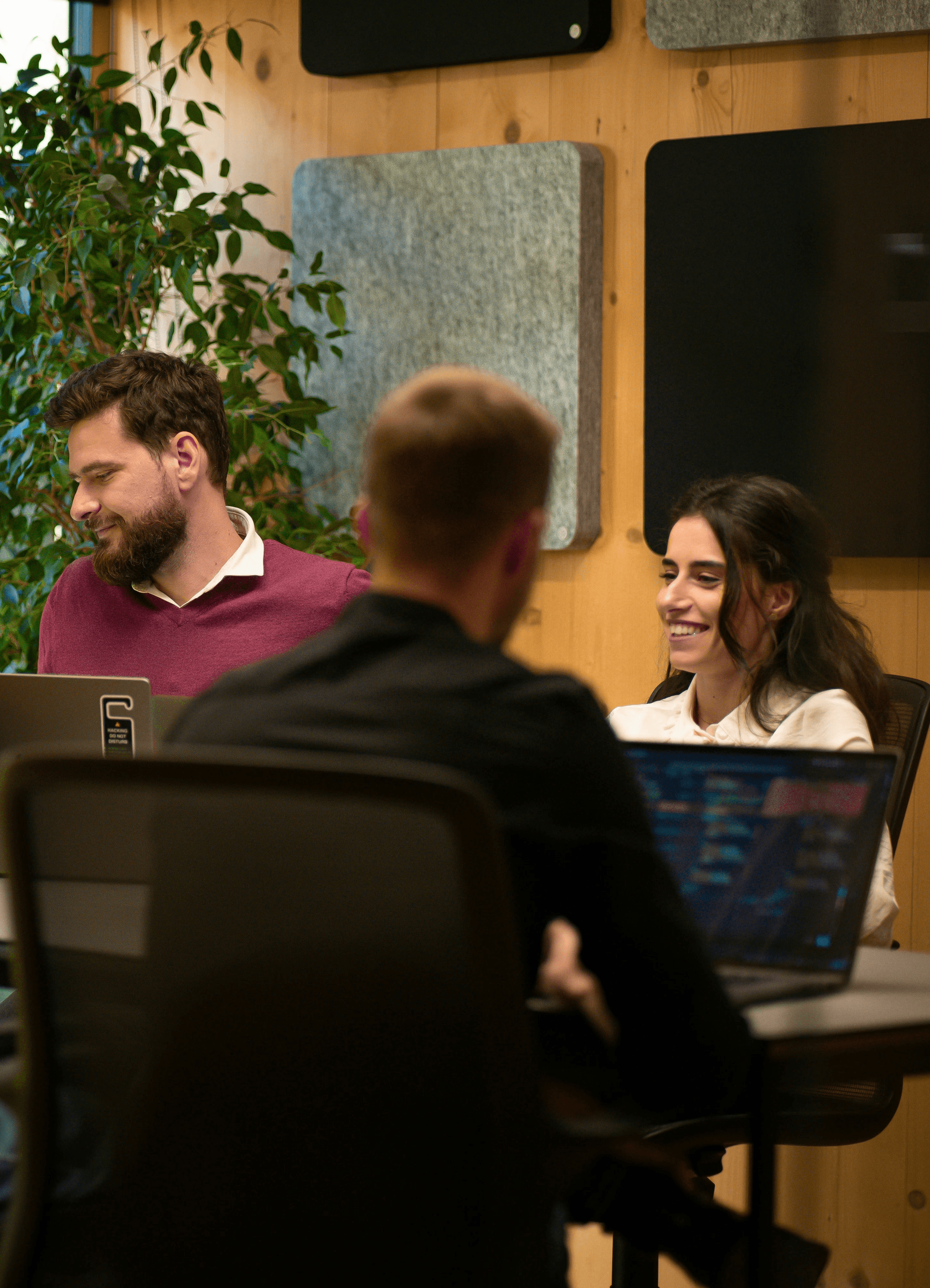 a group of people sitting around a table with laptops