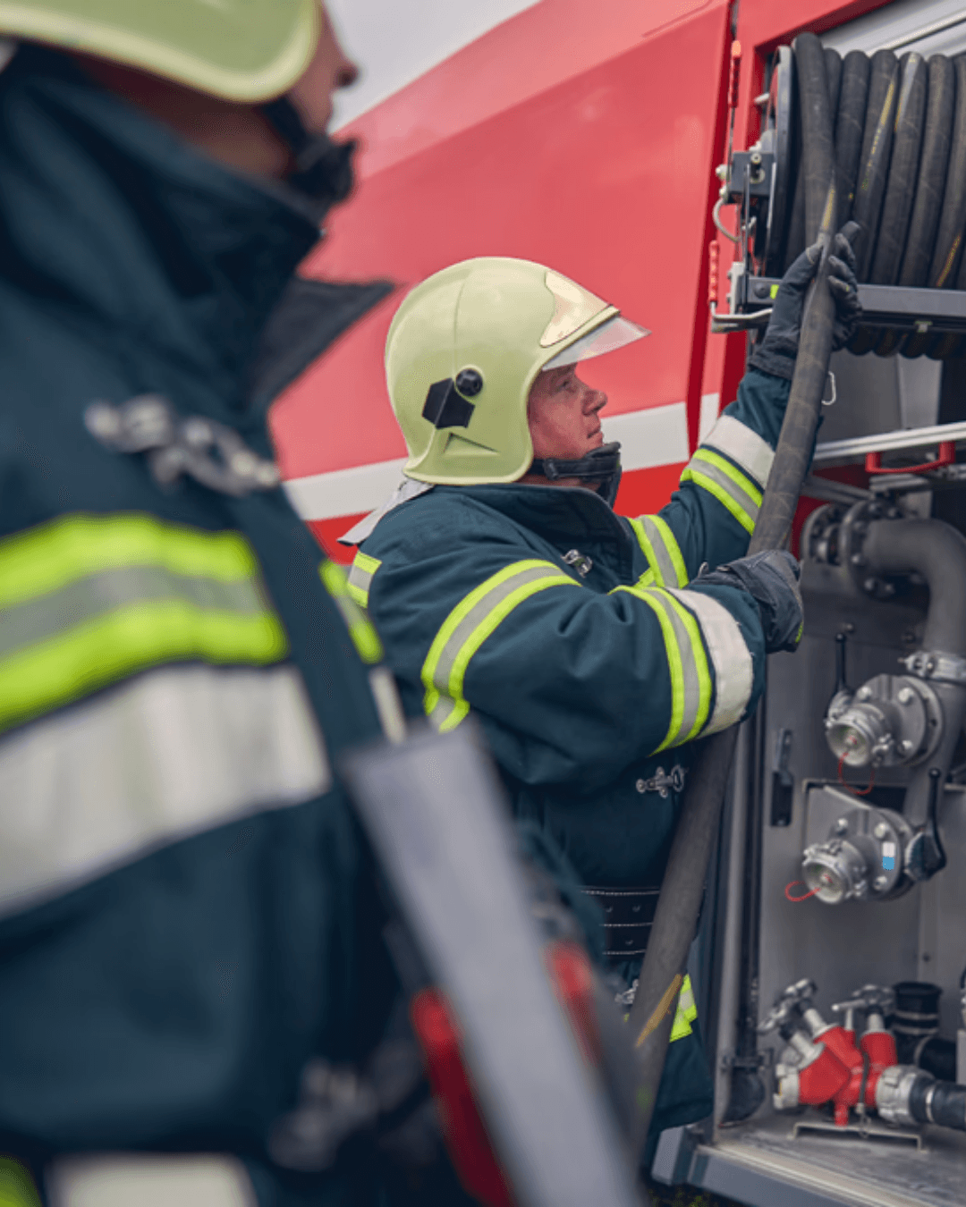 Firefighters preparing equipment on a fire service vehicle