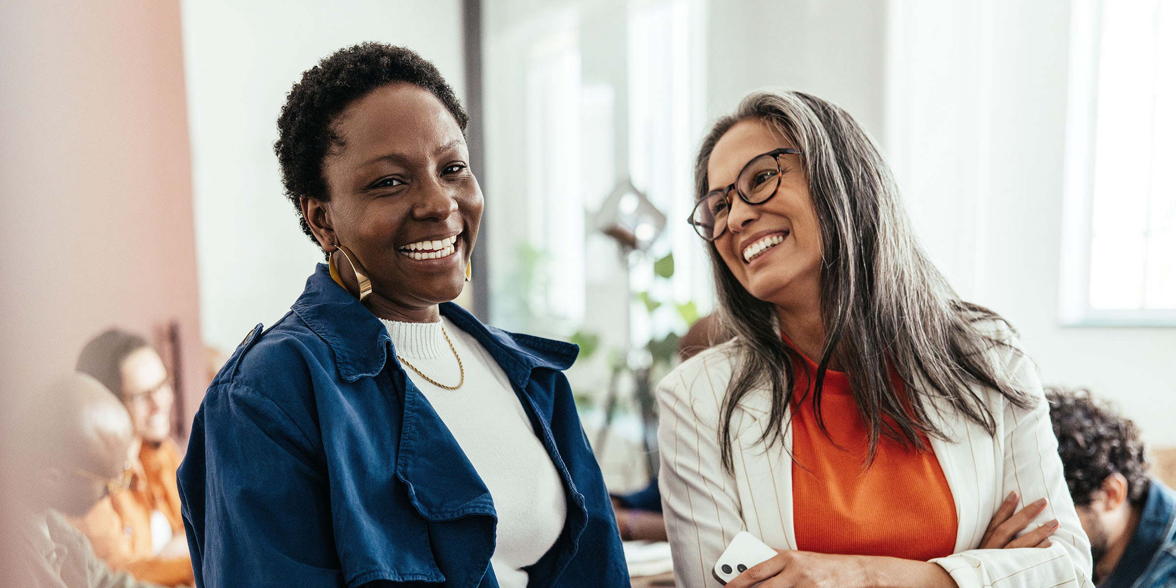 Two women chatting and laughing together in a meeting