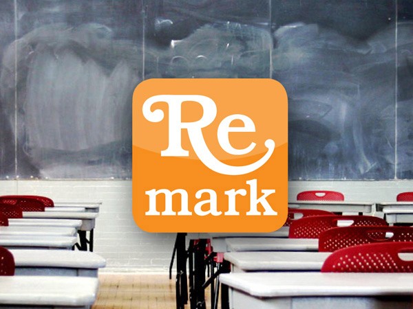 An orange square graphic with the white text "Re mark" is superimposed on a classroom scene. White desks with red chairs are arranged in rows facing a chalkboard with gray markings. The floor is light-colored wood.
