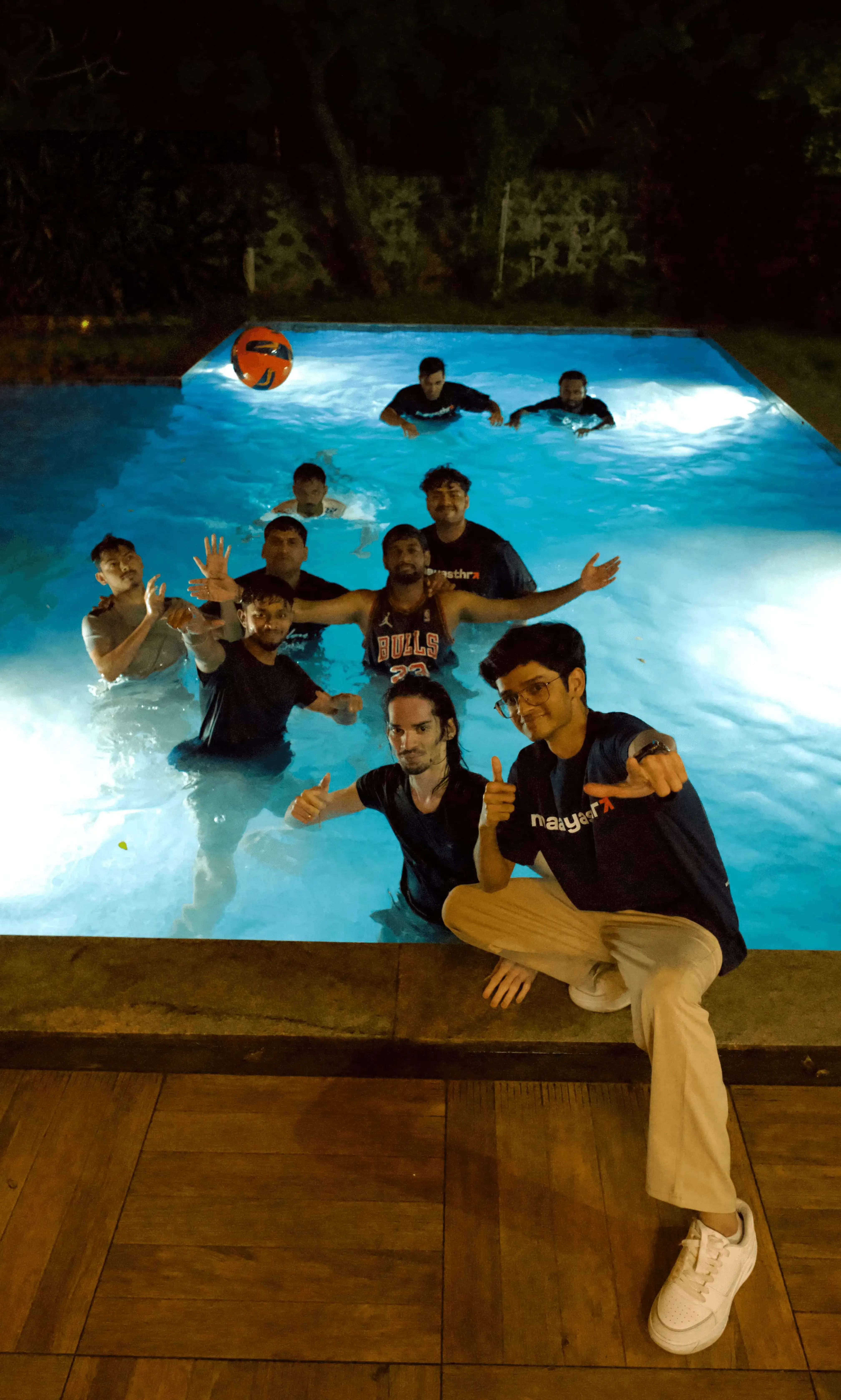 Team selfie featuring Maayasthra members wearing matching branded t-shirts, gathered indoors during a casual team meetup event.