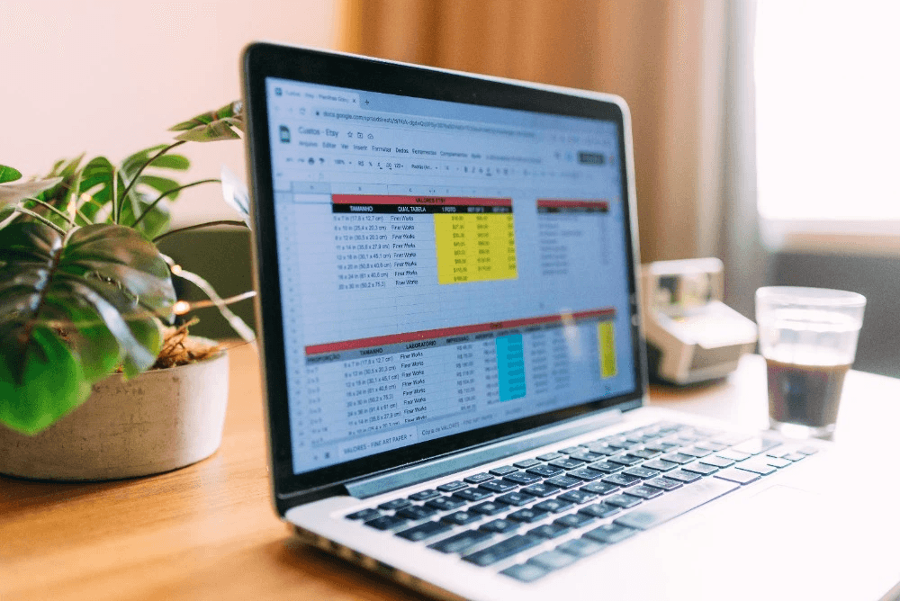 Laptop open with spreadsheet on desk - How to Combine Multiple Excel Sheets Into One