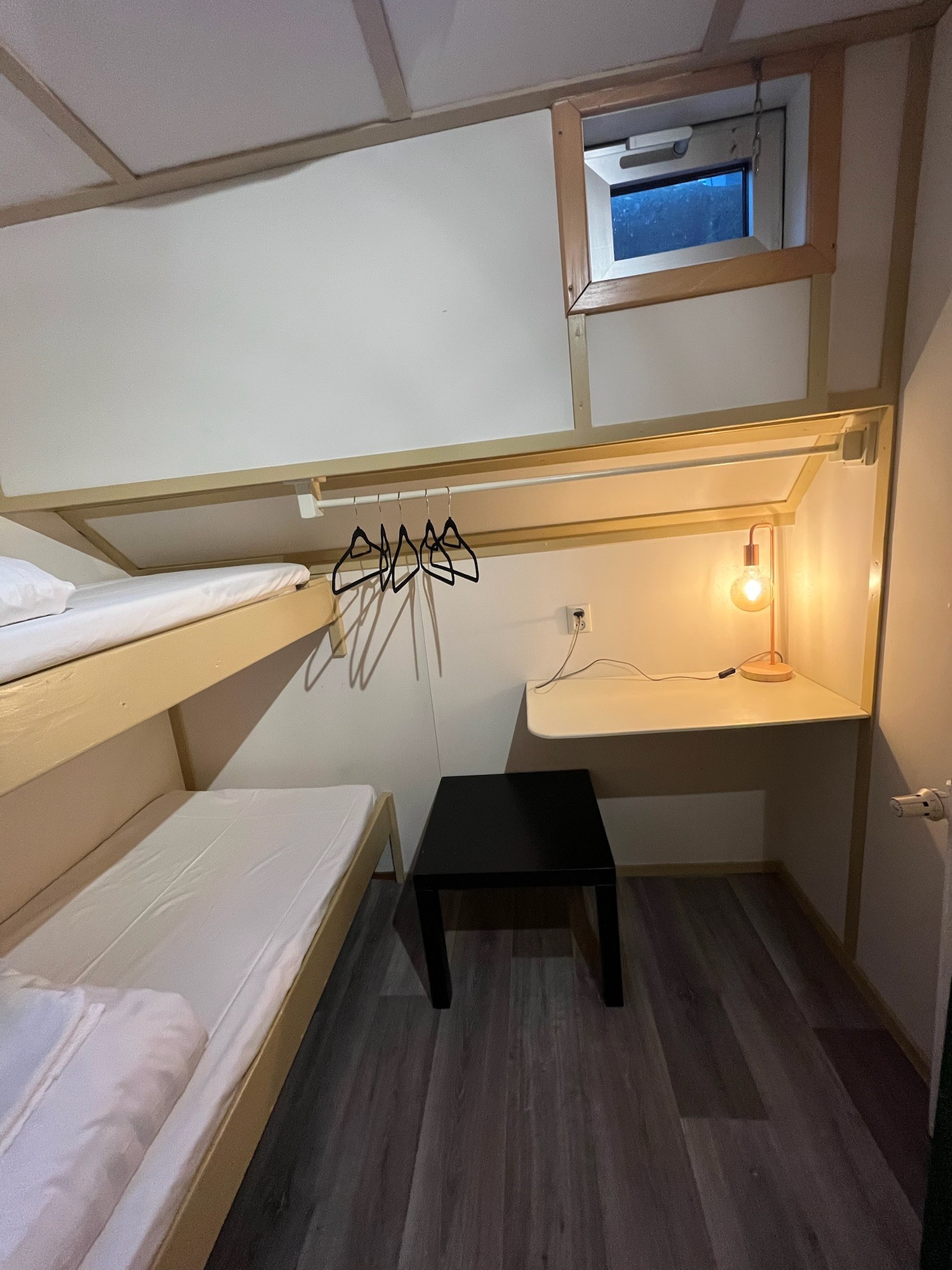 Beige upholstered bed with patterned pillows and ottomans