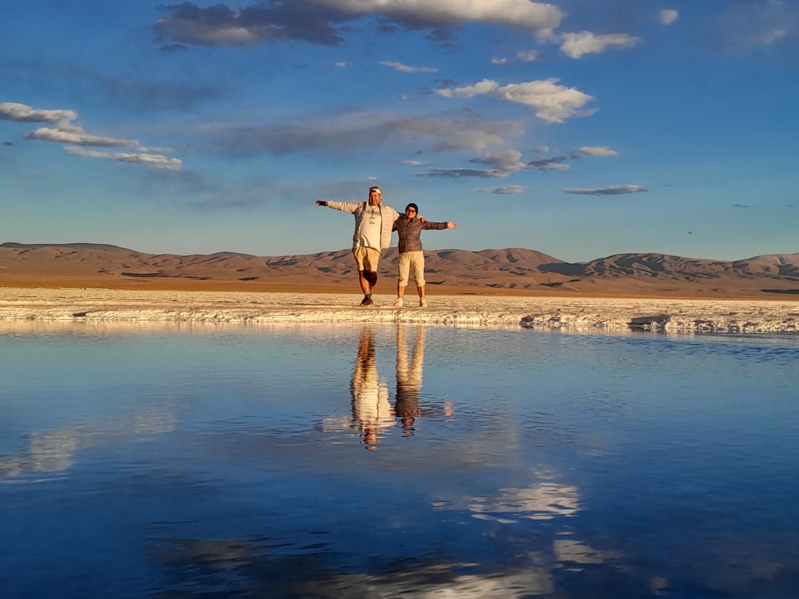 Mujer sentada sobre un tronco frente a una cascada doble en un bosque frondoso de Argentina.