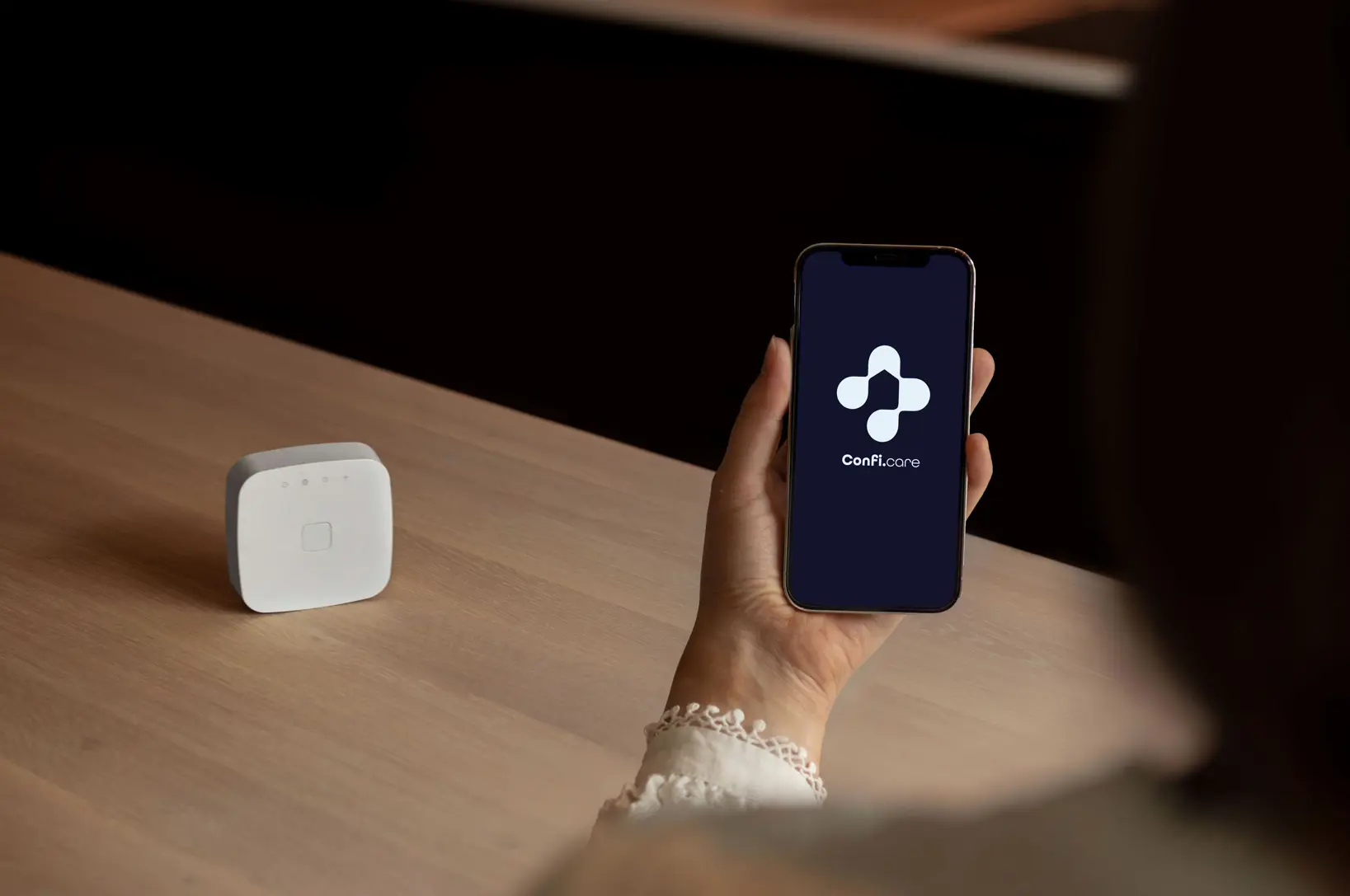 Hånd som holder en telefon med Confi.care app