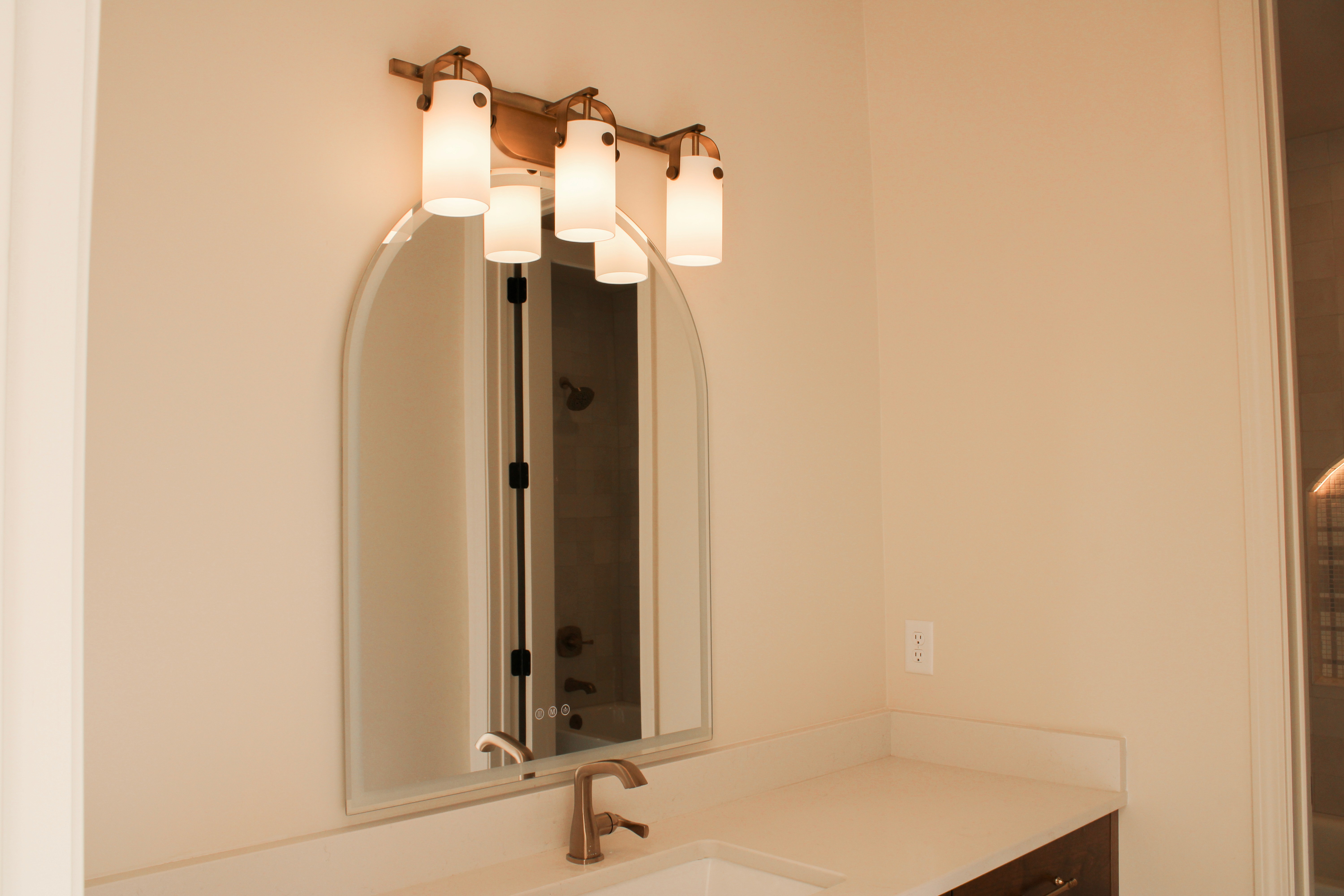 Vanity area in a bathroom and an arched mirror above the countertop in a St. George, Utah home.