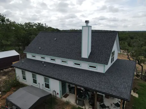 Dark architectural shingles on a San Antonio farmhouse; illustrative completed roof, not a documented cold-weather installation.