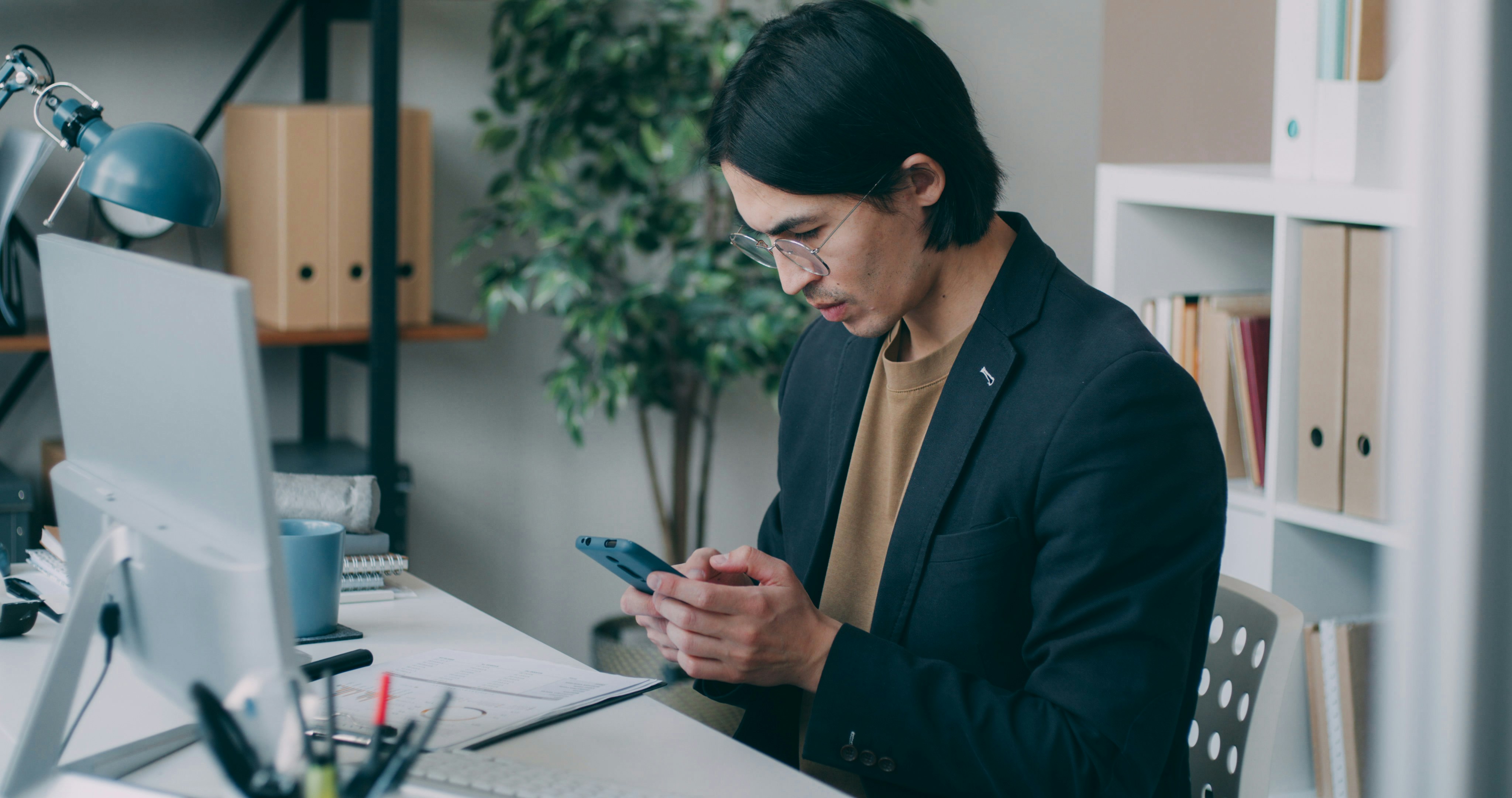 a-man-sitting-at-a-desk-using-a-cell-phone - vitaly-gariev (unsplash)./pho