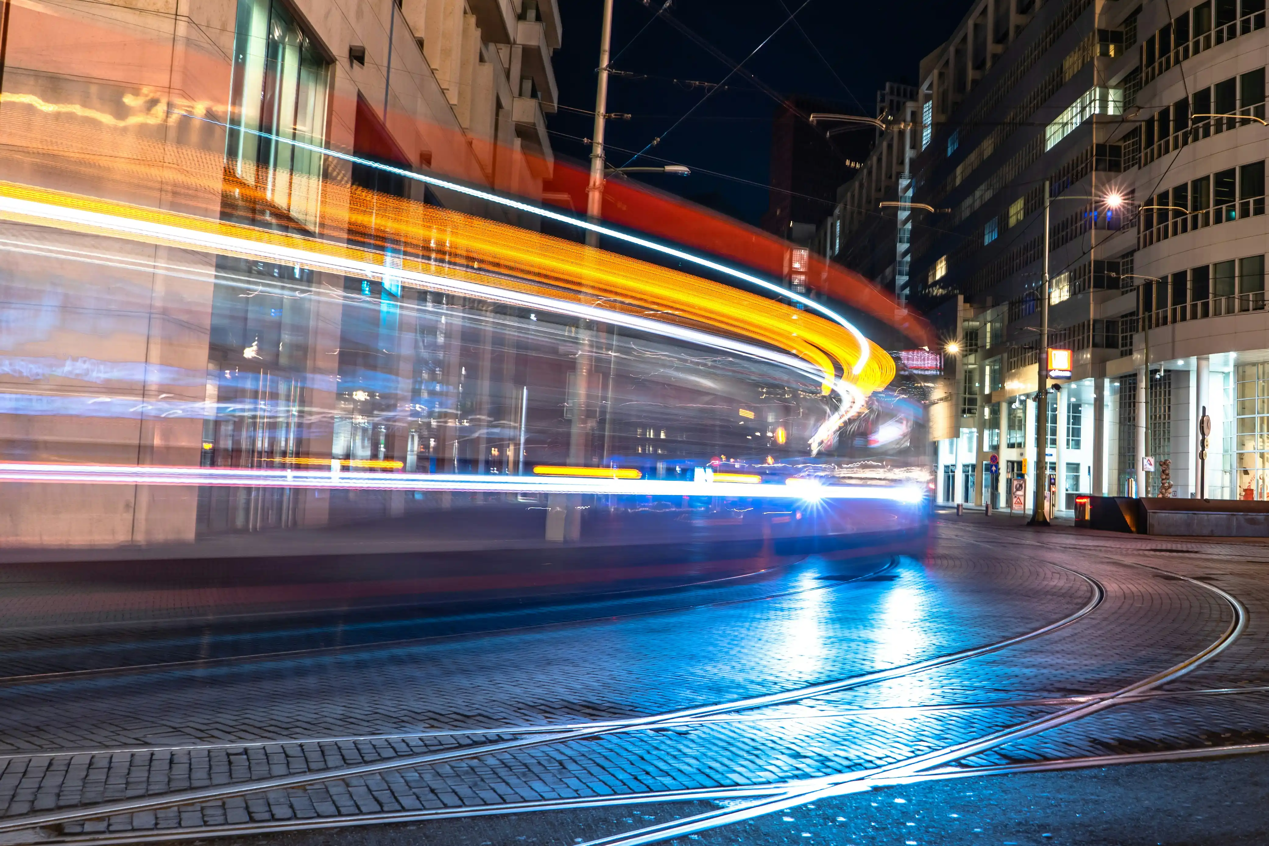 Nachtelijk straatbeeld in Den Haag met tramsporen en lichtstrepen