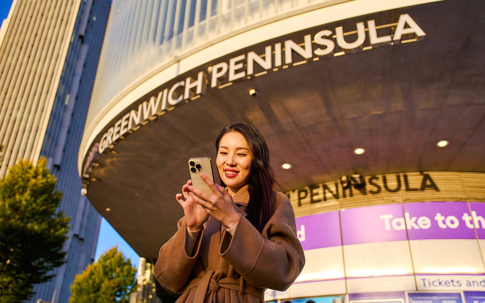 Guest using phone at Greenwich Peninsula, London near IFS Cloud Cable Car.