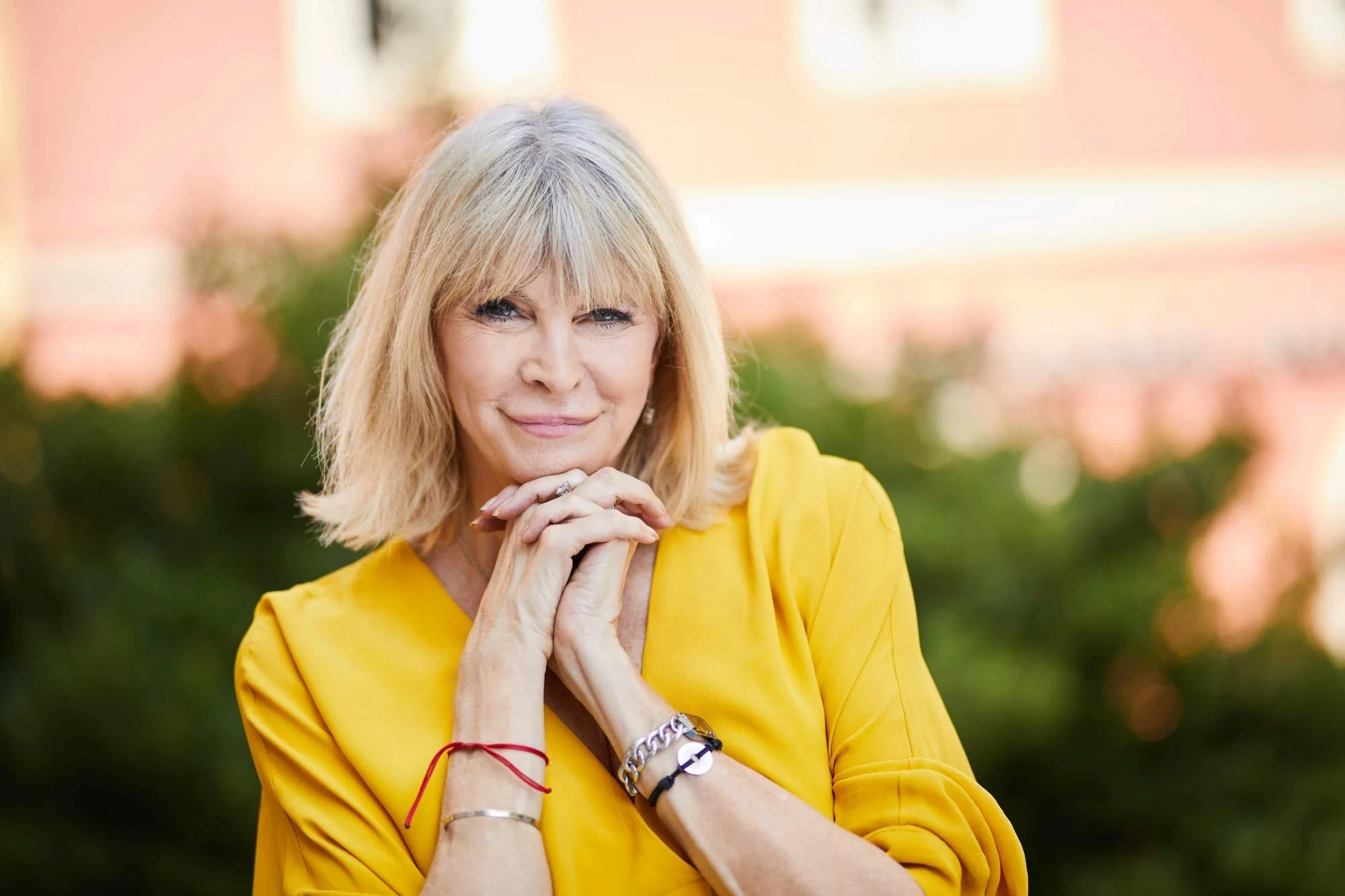 Confident smiling Marisa Peer in yellow symbolizing empowerment and inner transformation.