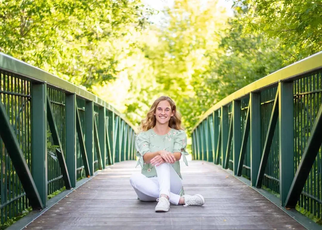 Senior girl sitting in the middle of a green footbridge