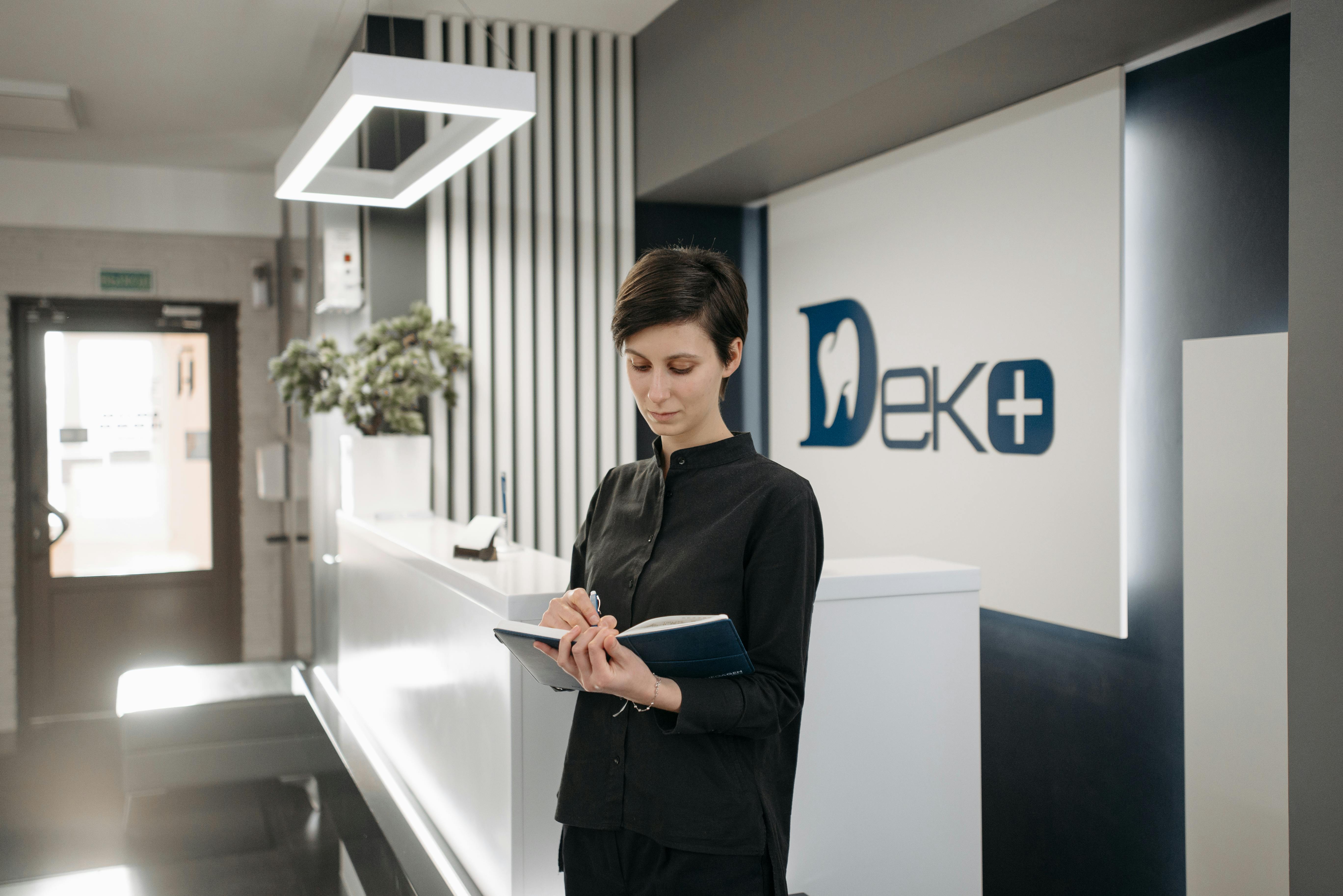 Woman standing with planner at front desk of a dental practice