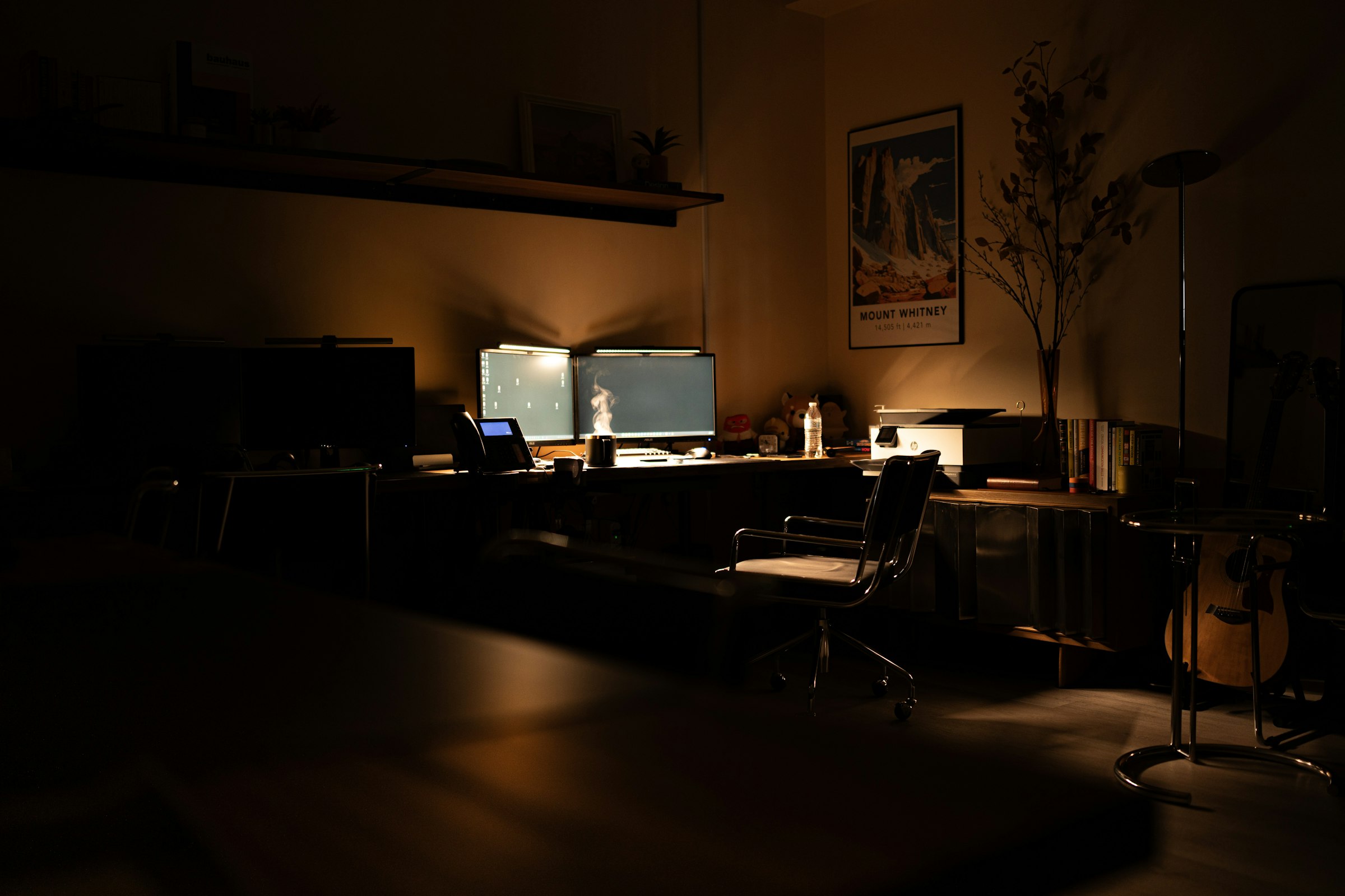 A dimly lit dual-monitor developer workstation, representing a dedicated software engineering team in Indonesia