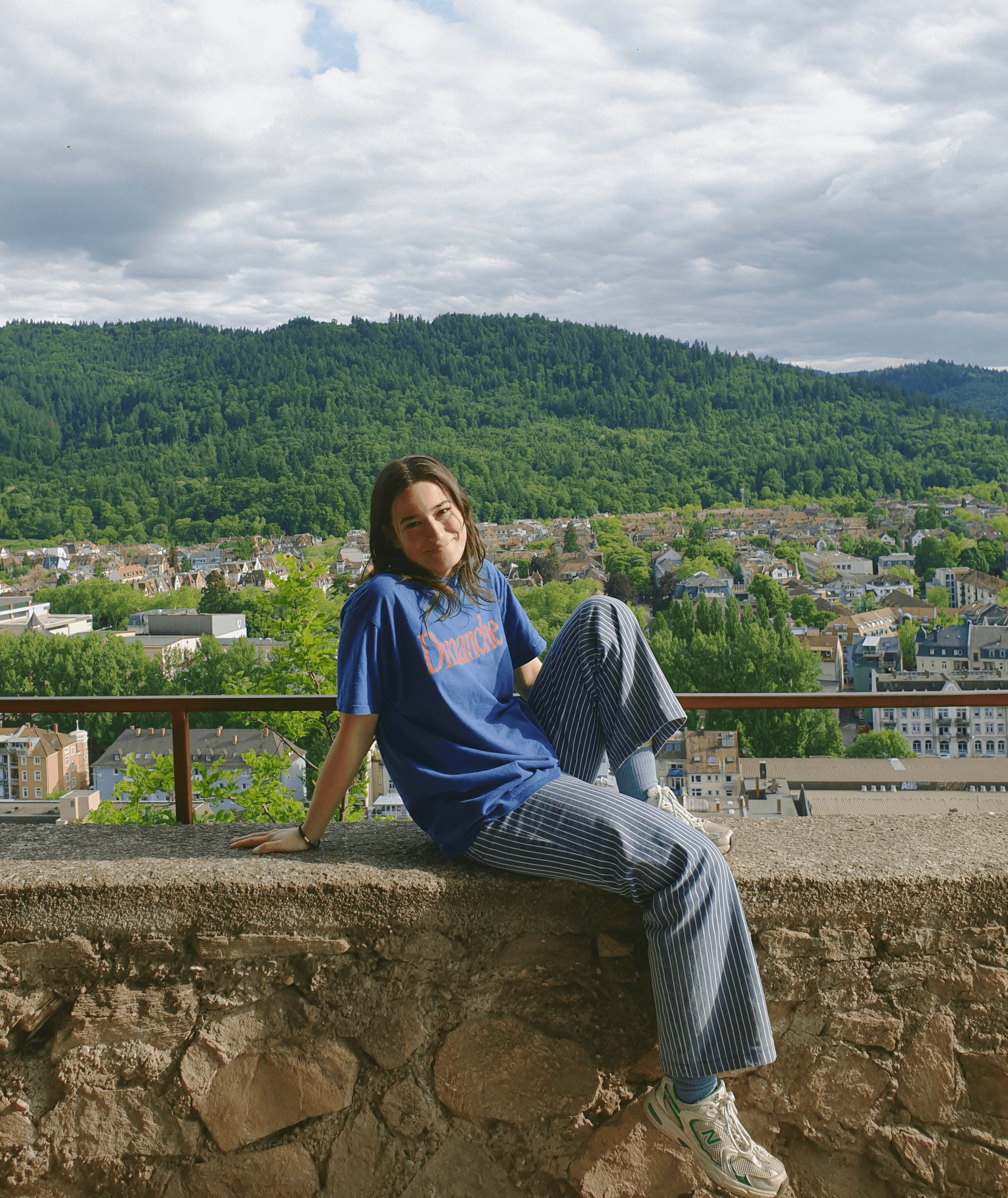 Me sitting by a view of a city and forest