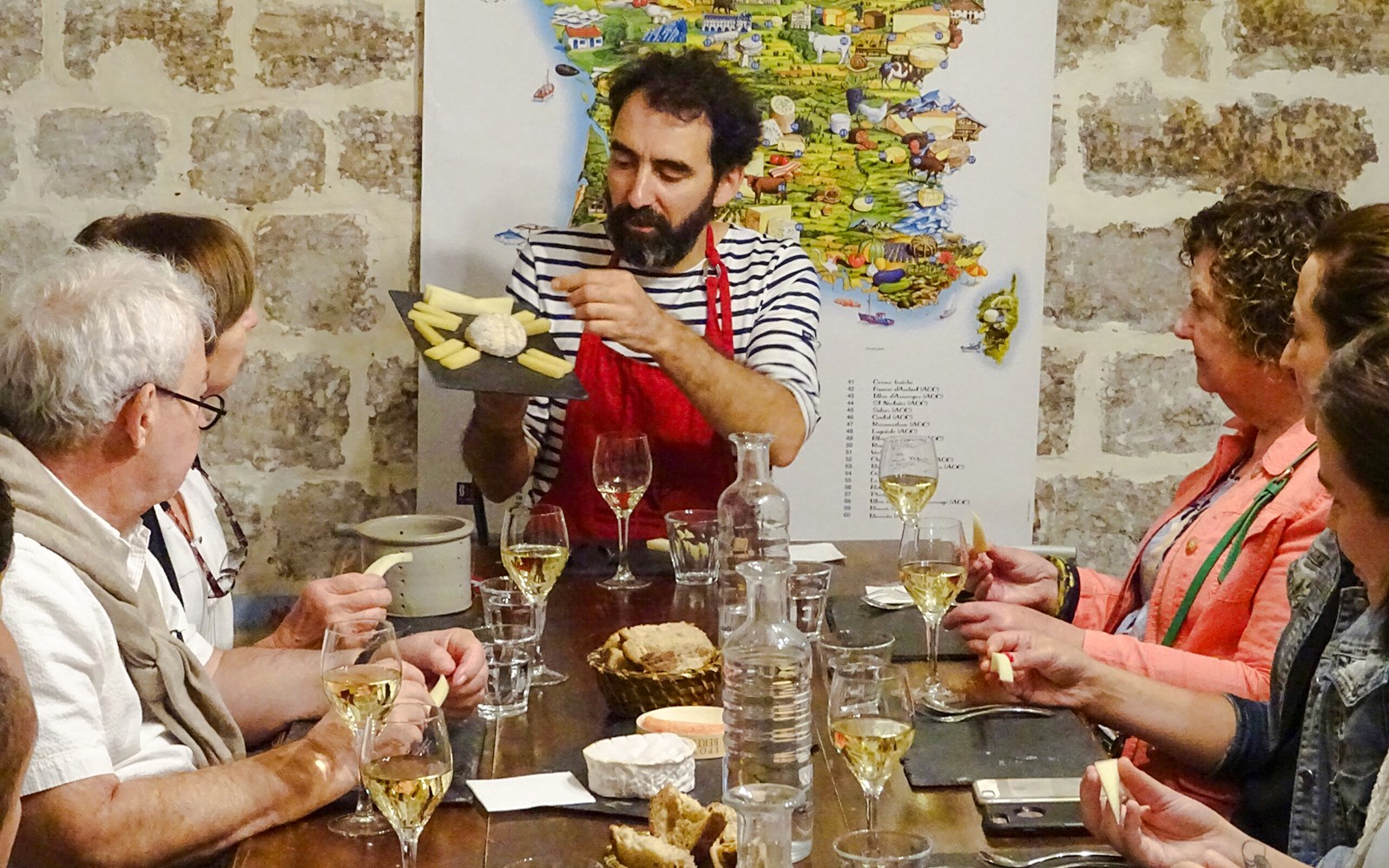 Paris, Fransa'daki Peynir Müzesi'nde bir uzman, masanın etrafında oturan ziyaretçilerle peynir çeşitlerini tartışıyor.