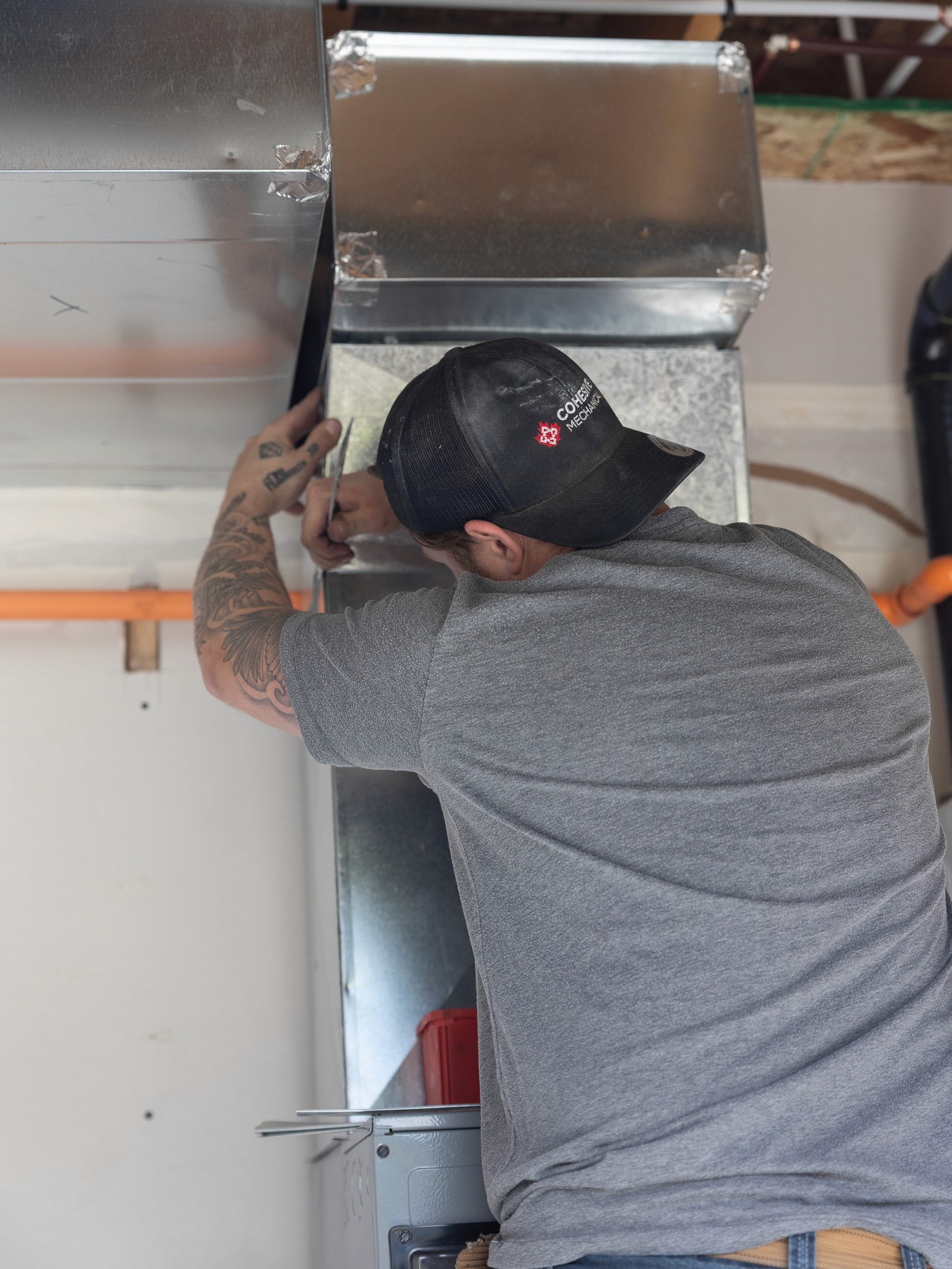 HVAC technician working on ductwork in Chilliwack, Fraser Valley, British Columbia, for plumbing and pipefitting services.