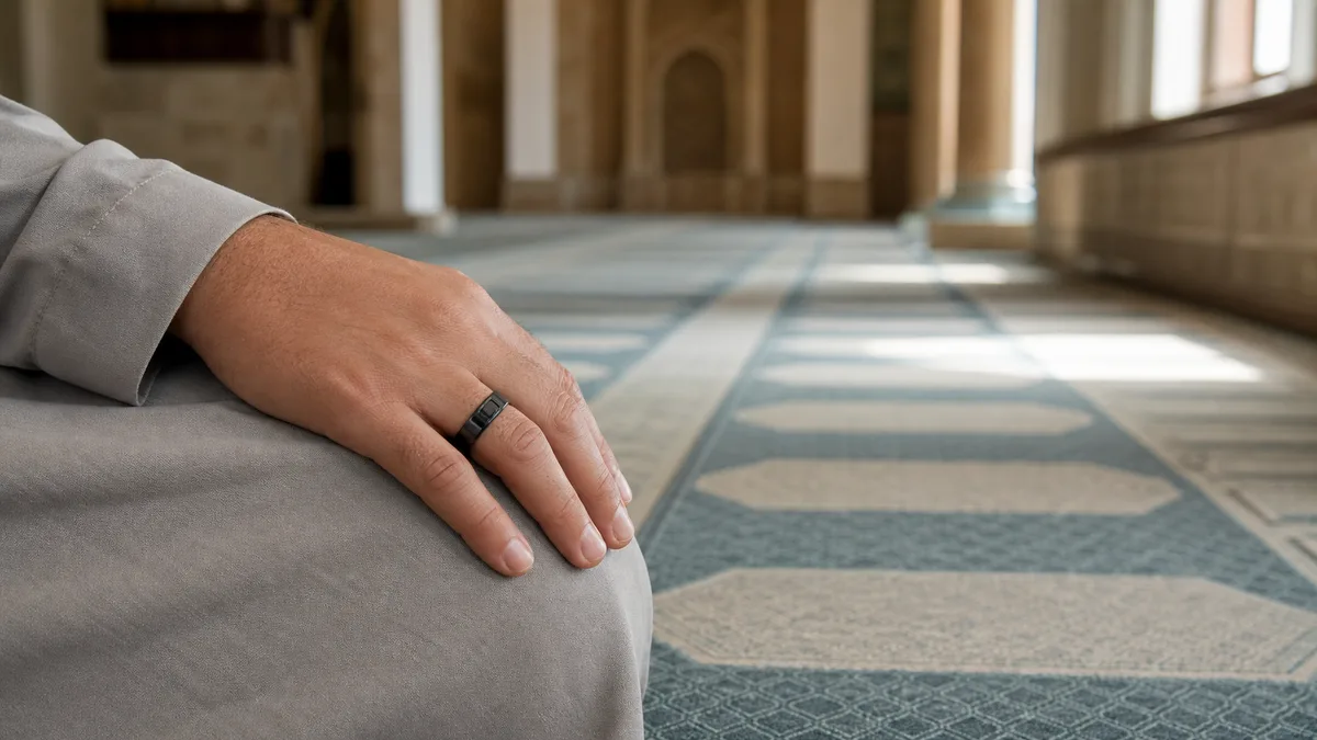 Hand rests on the knee in a quiet mosque while wearing a smart zikr ring