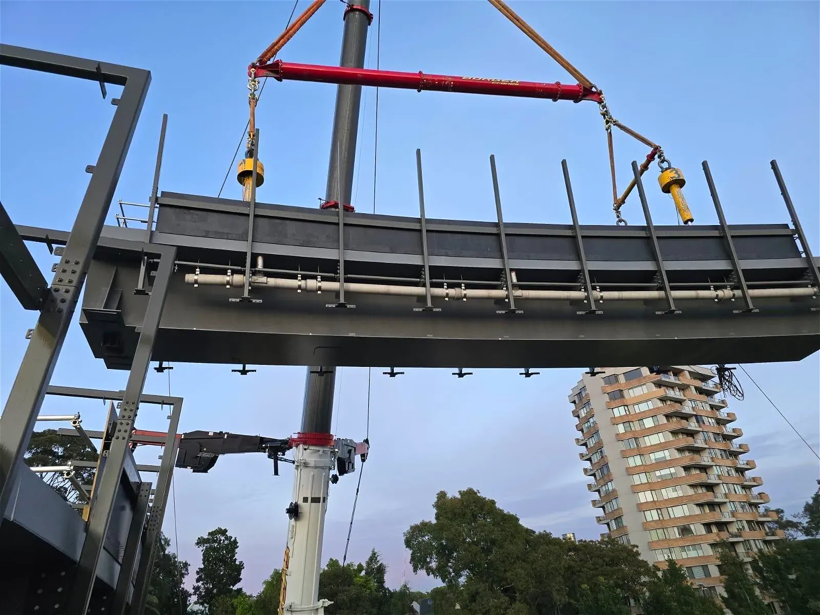 Heavy object being lifted by crane near building.