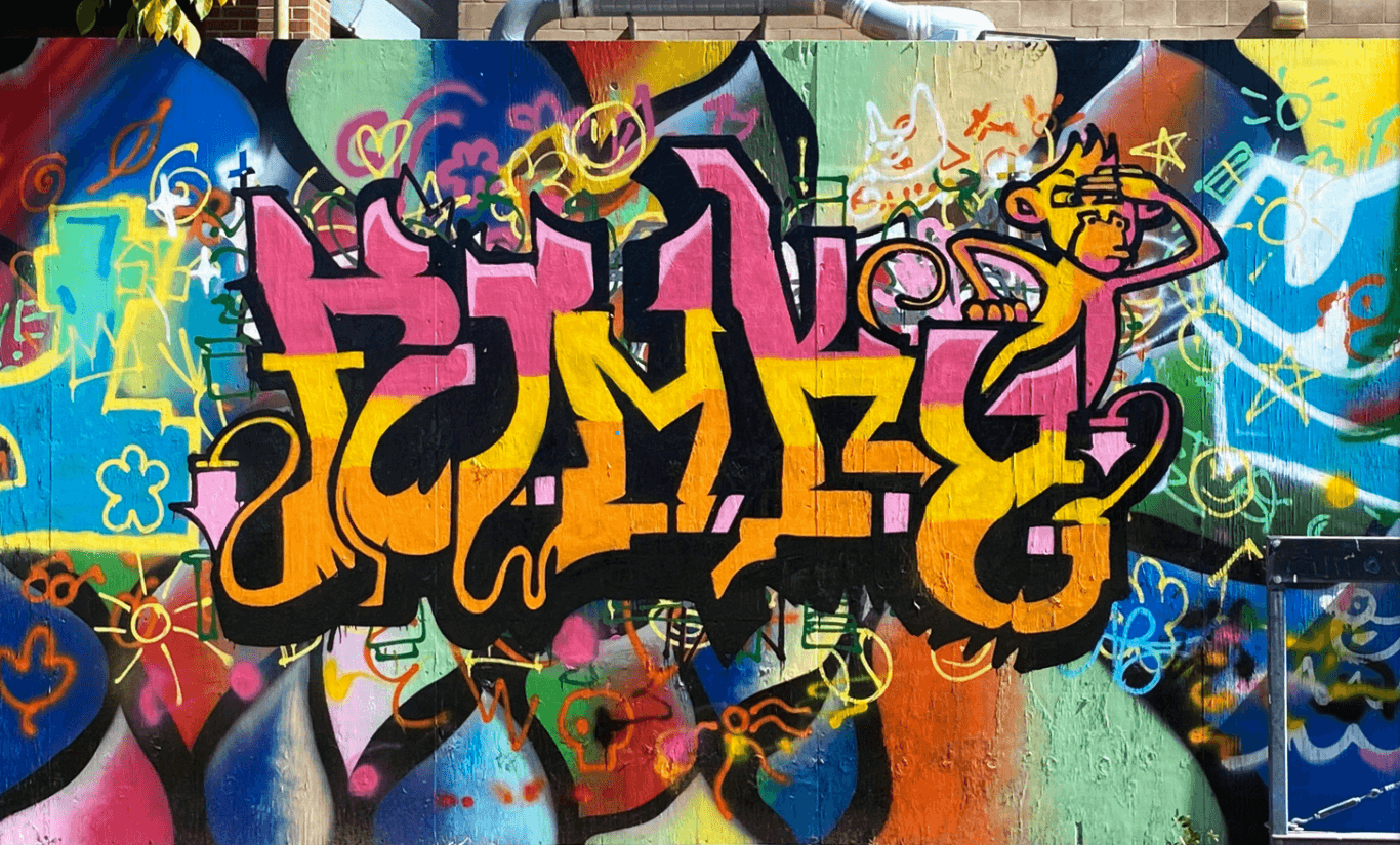 Pink, yellow, and orange graffiti wall art spelling "FUNKY," with a monkey as a visual accent.