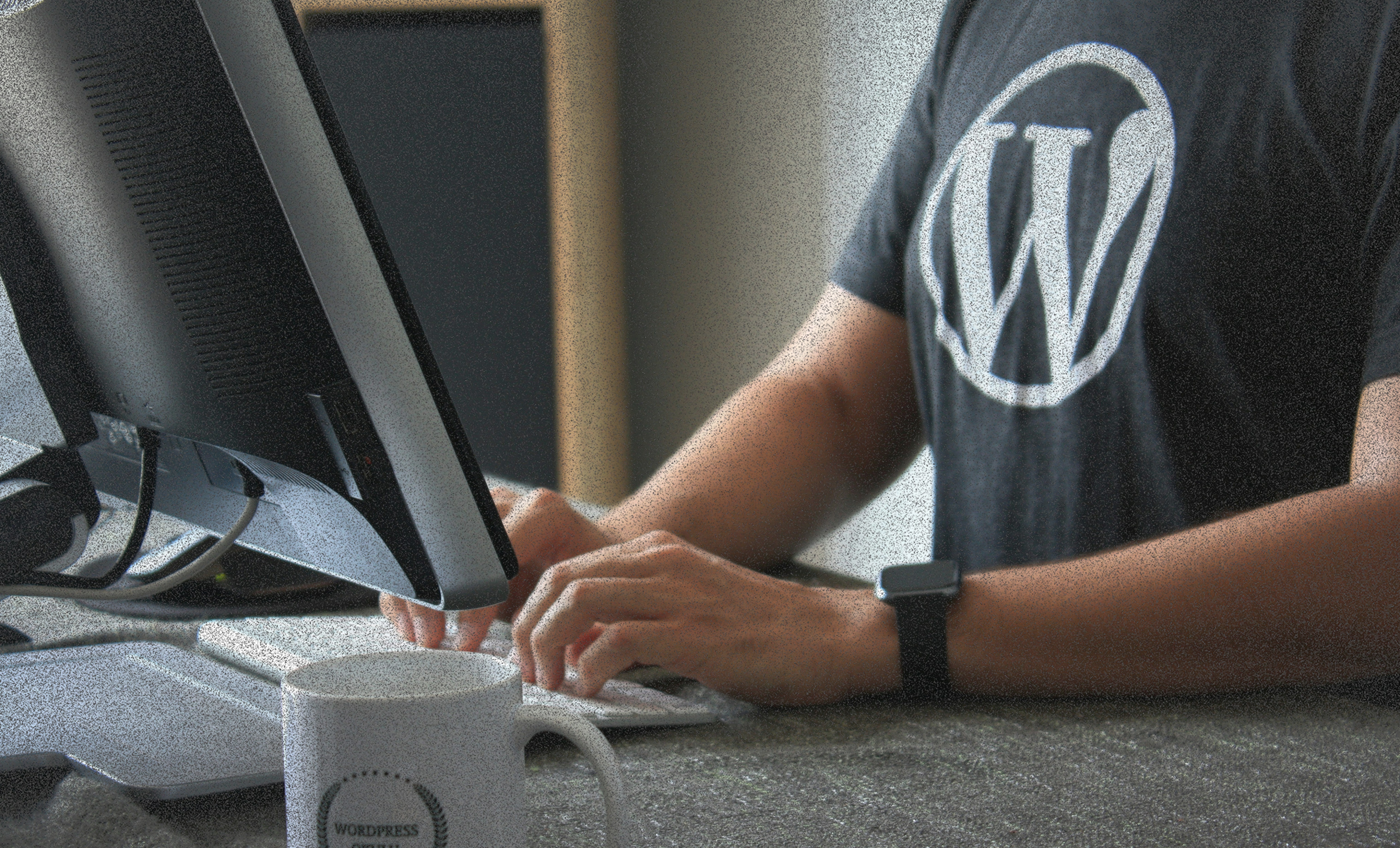 Black and white image of people working at a table with laptops, showing hands gesturing during discussion of digital content displayed on screens, with fabrica® logo in the corner.
