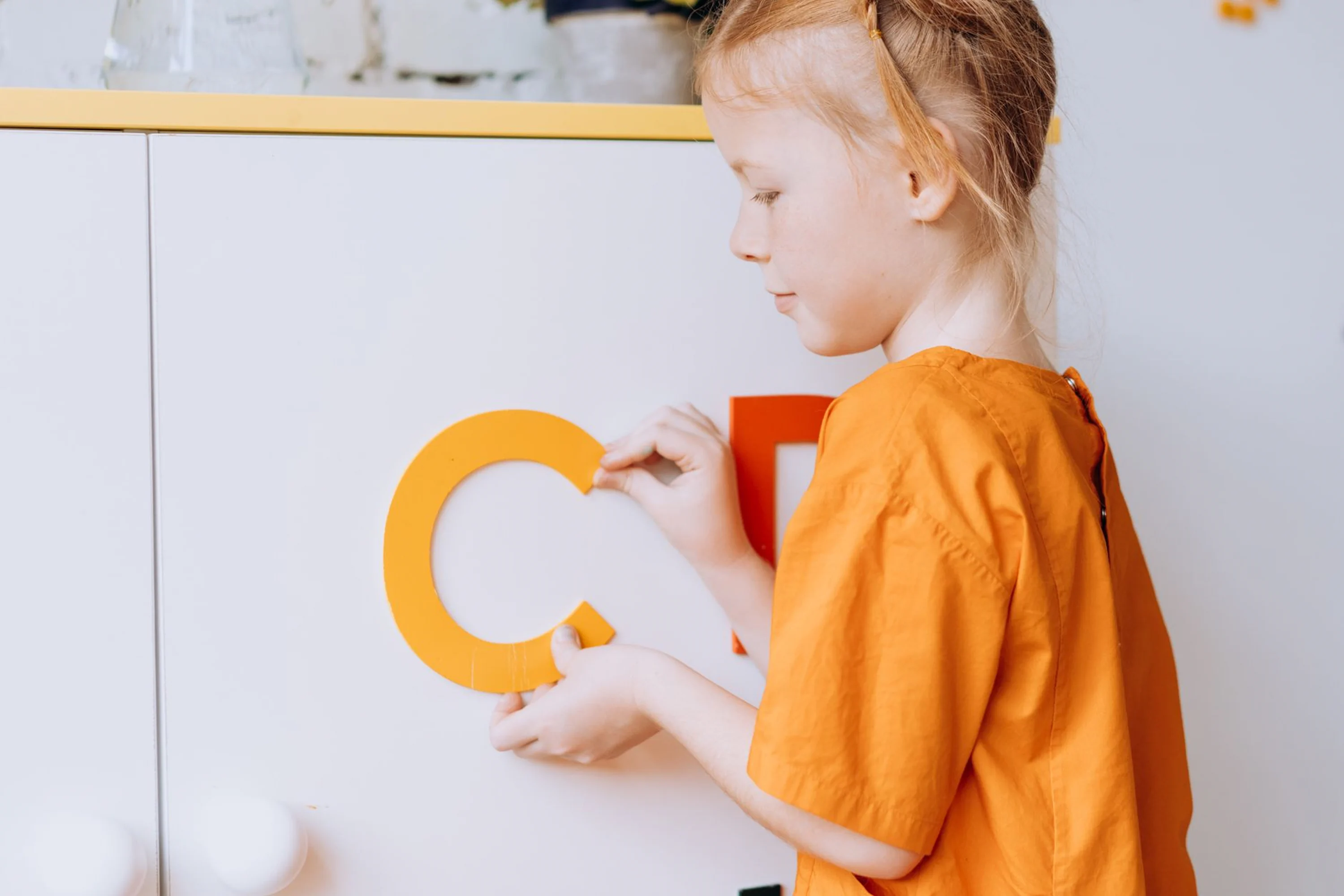 A preschool child learning letters through a playful classroom activity.