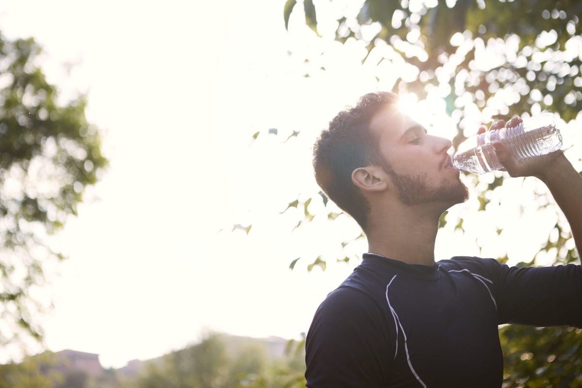 A man drinks water outside.