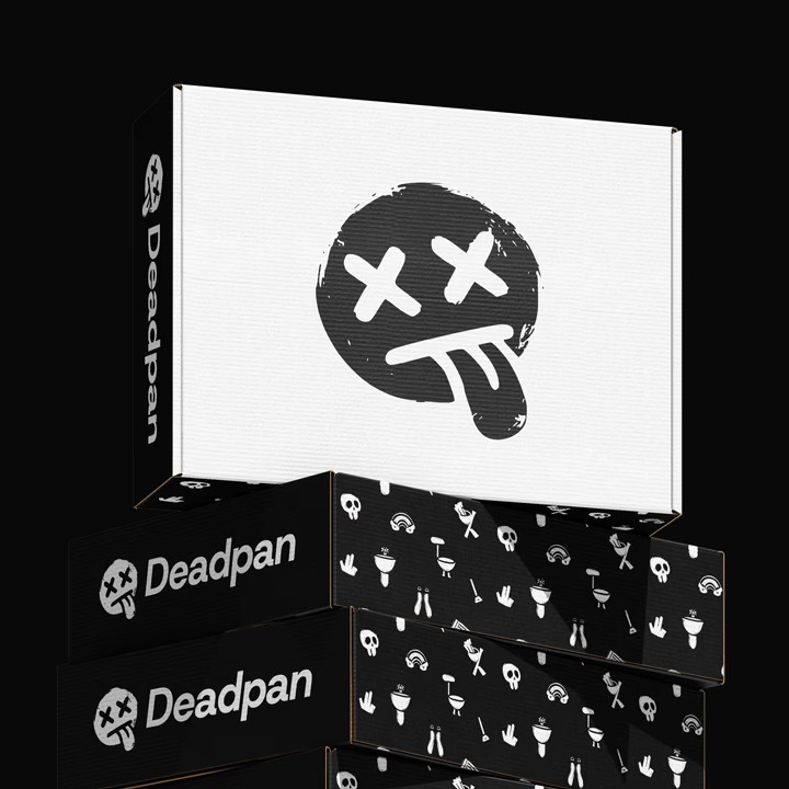 Stack of black-and-white Deadpan shipping boxes: a large white box on top with a distressed black smiley face logo (X eyes, tongue out), and beneath it several black boxes printed with small white icon patterns and “Deadpan” branding on the sides, all against a pitch-black background.