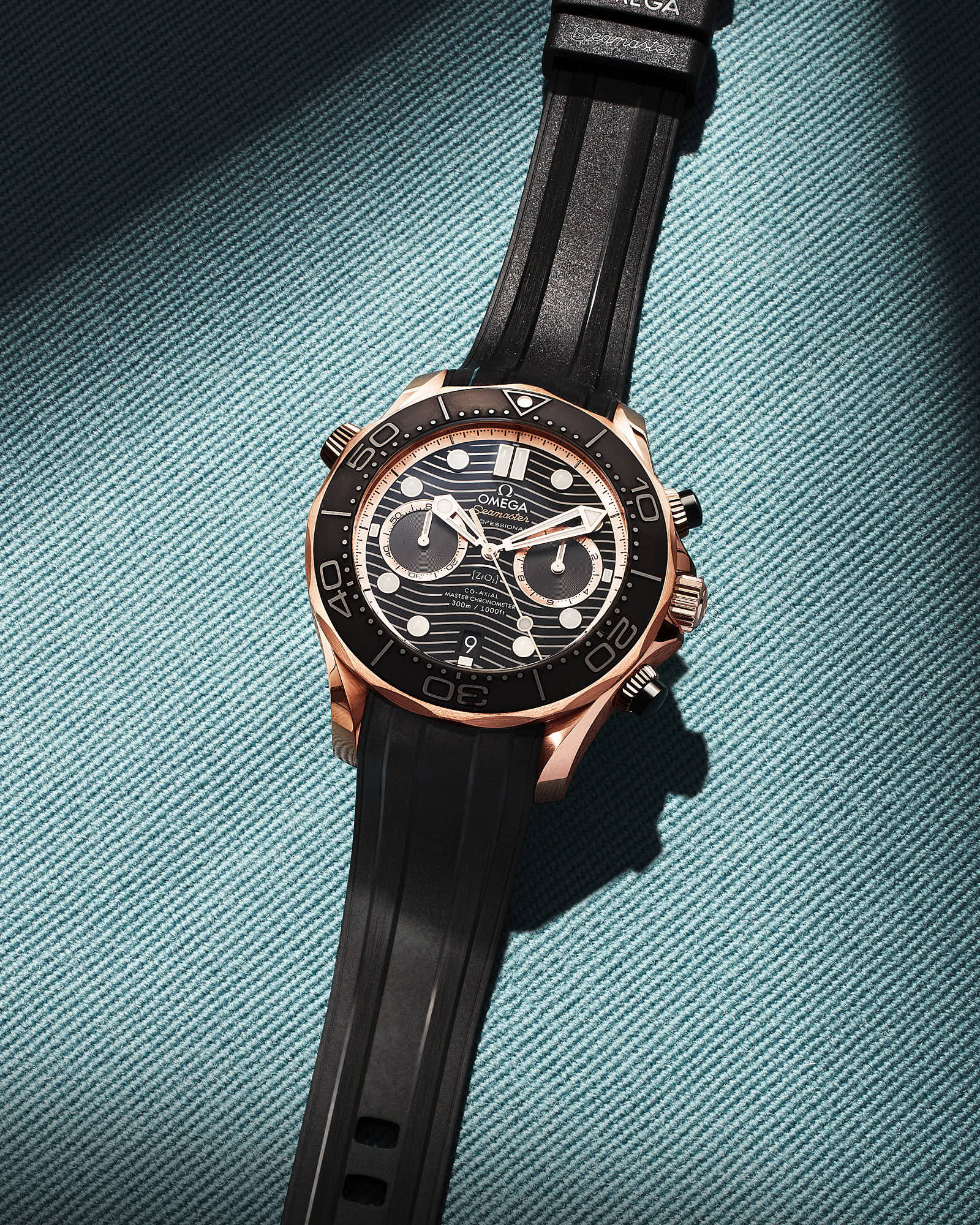 Luxury Omega Seamaster watch with black dial and rubber strap on textured background.