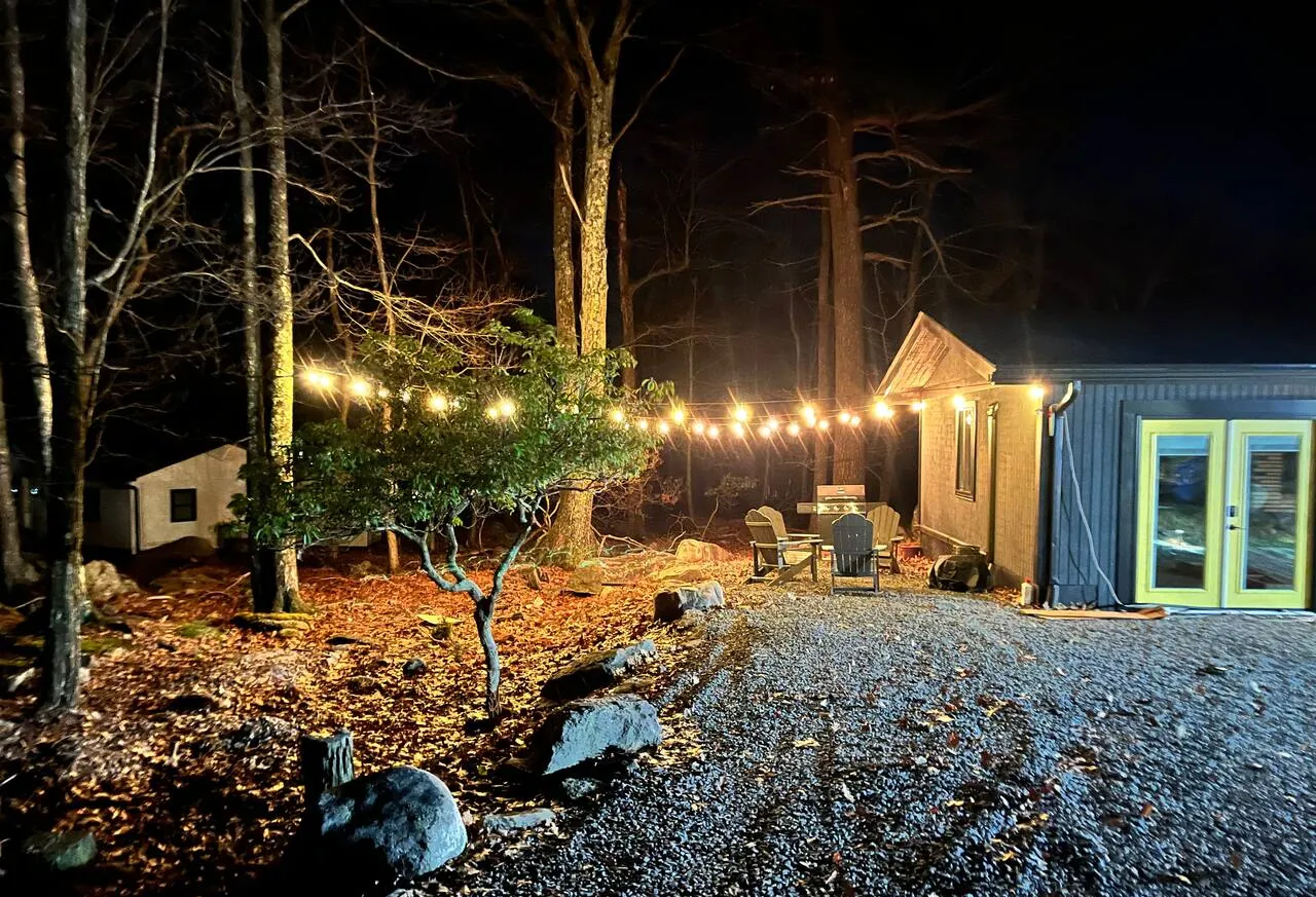 Cabin yard lit by string lights at night at The Love Shack, Lake Harmony, PA
