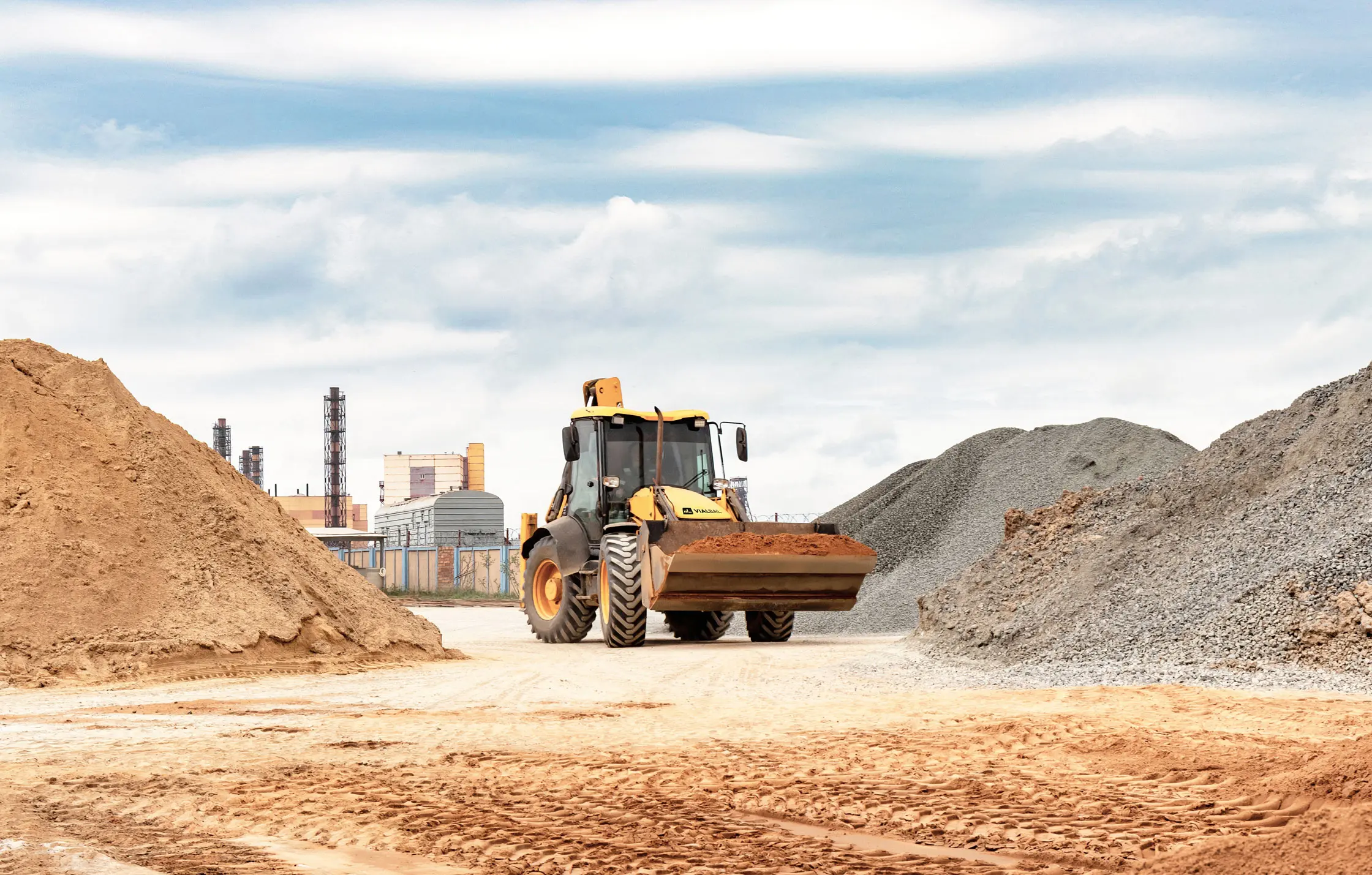 Retroexcavadora VialBal de la marca XCMG trabajando en corralón de materiales.